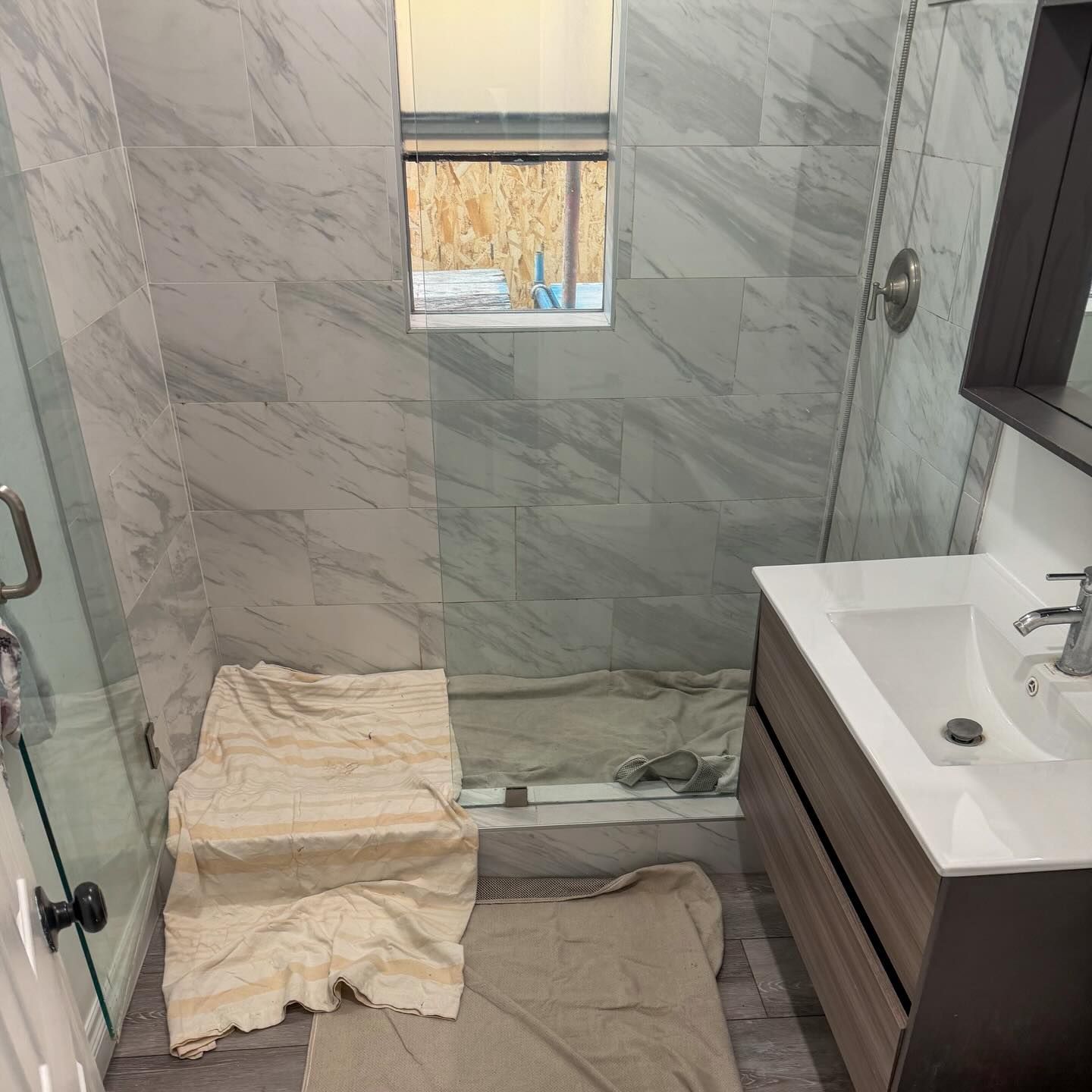 Small marble-tiled bathroom with a toilet under a towel and a sink vanity on the right.