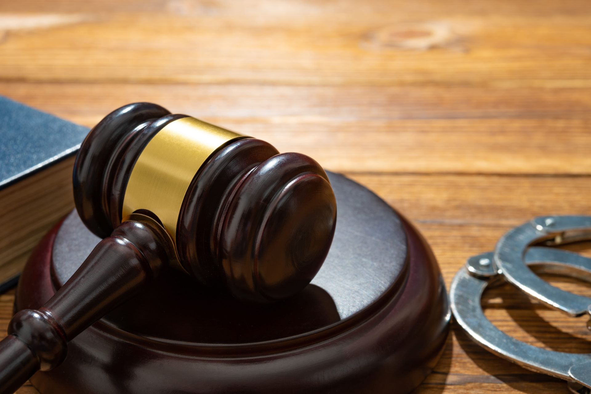 Judge’s gavel on a wooden desk beside handcuffs, symbolizing law enforcement and justice