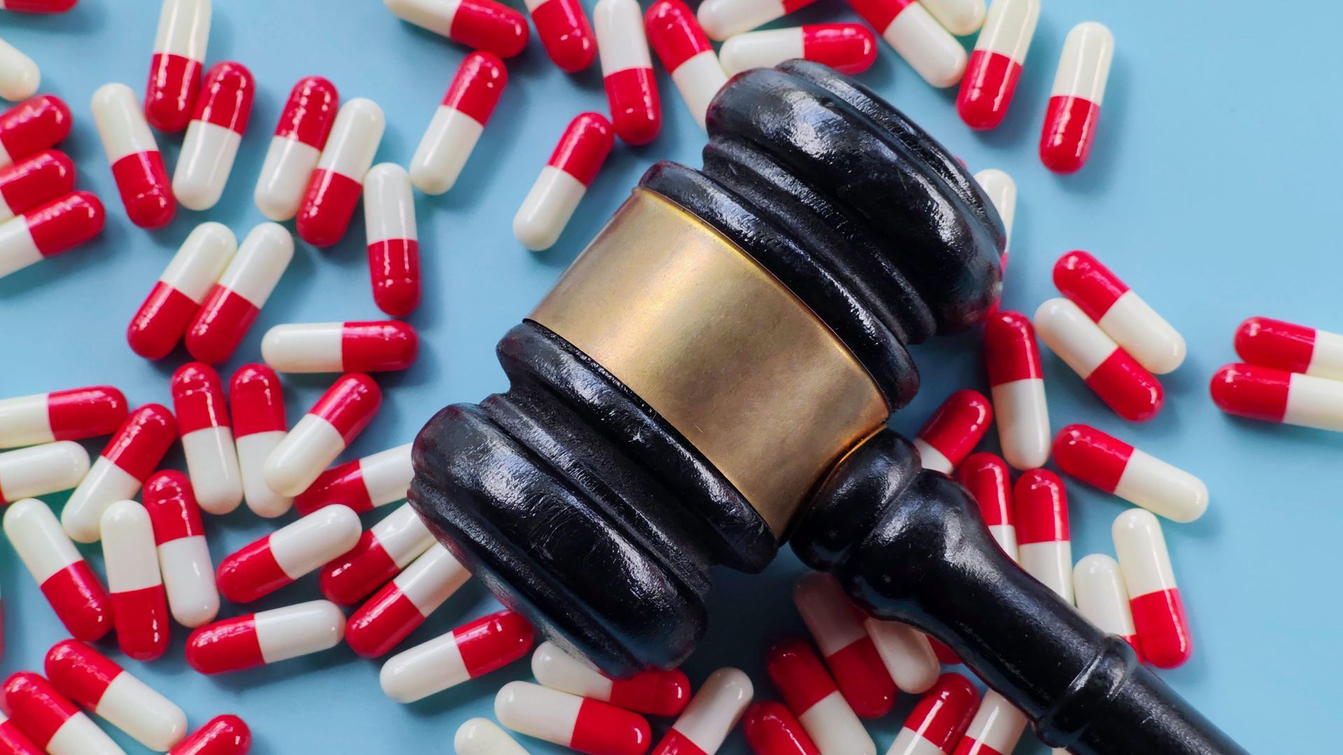 Judge’s gavel surrounded by red and white capsules, symbolizing legal issues around medication or drugs