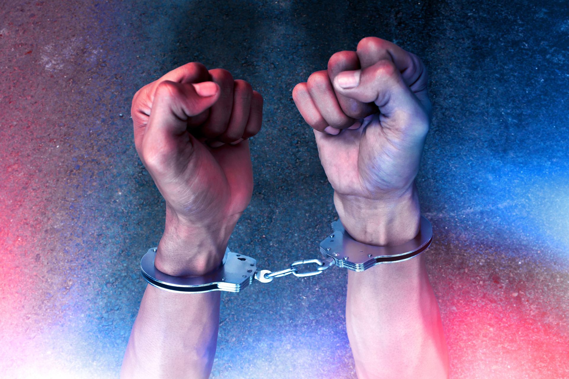 Raised handcuffed fists against a red and blue smoky background