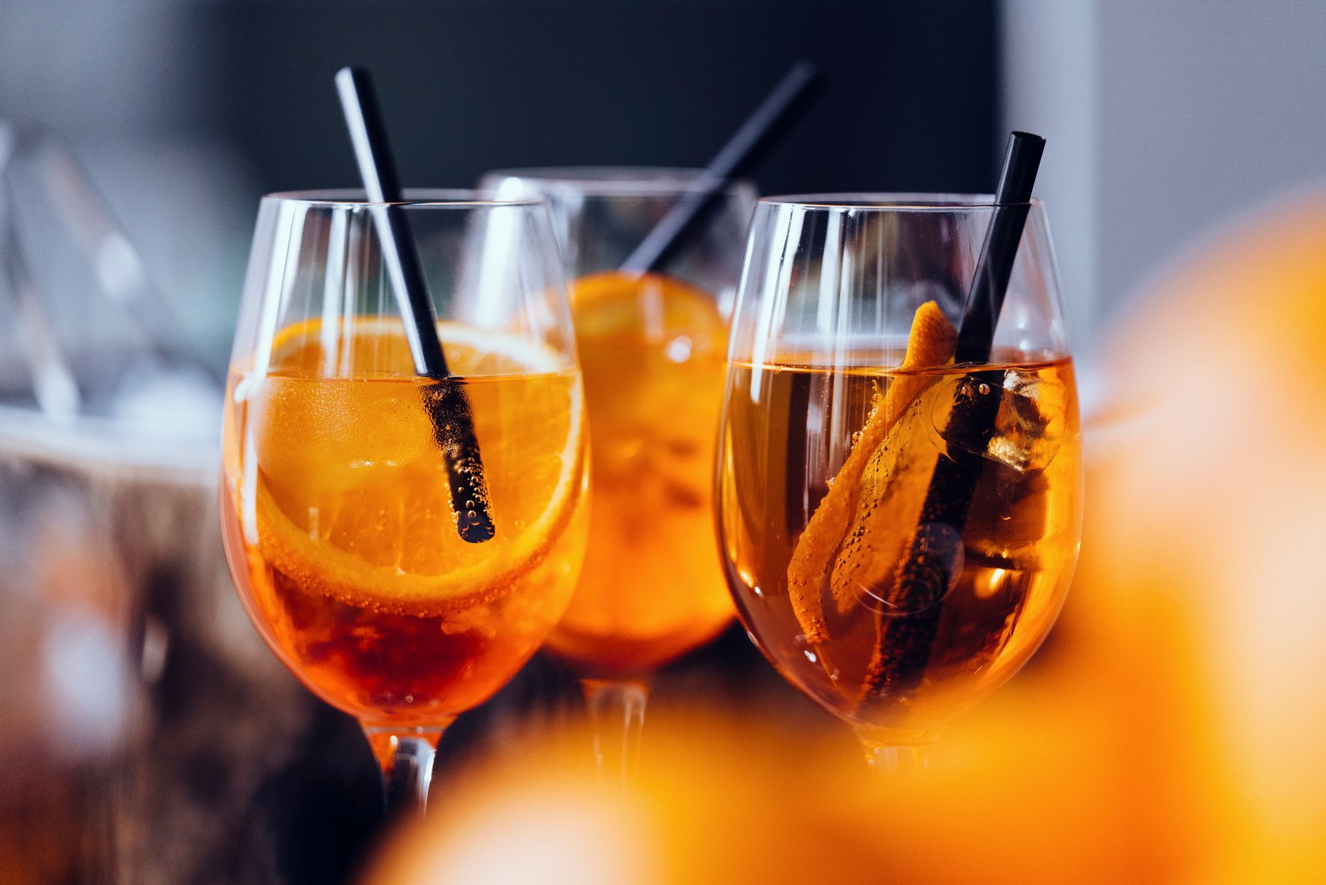 Tre bicchieri di succo d'arancia con cannucce su un tavolo.