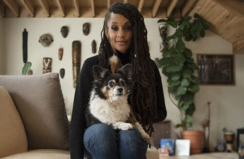 Woman seated indoors with two small dogs in a cozy living room