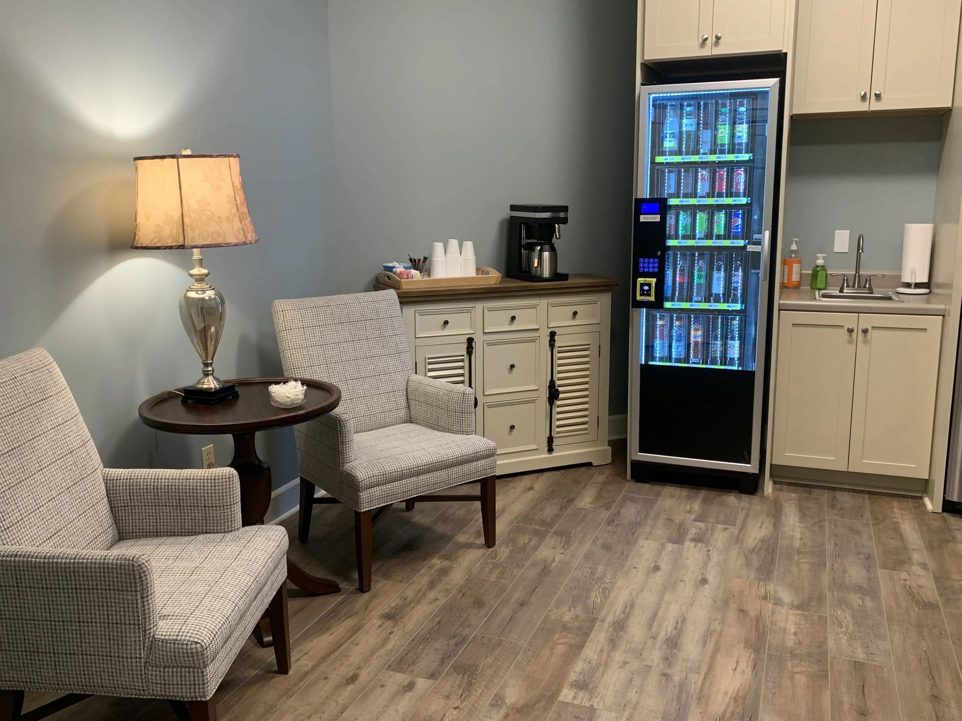 a room with two chairs , a table , and a vending machine .