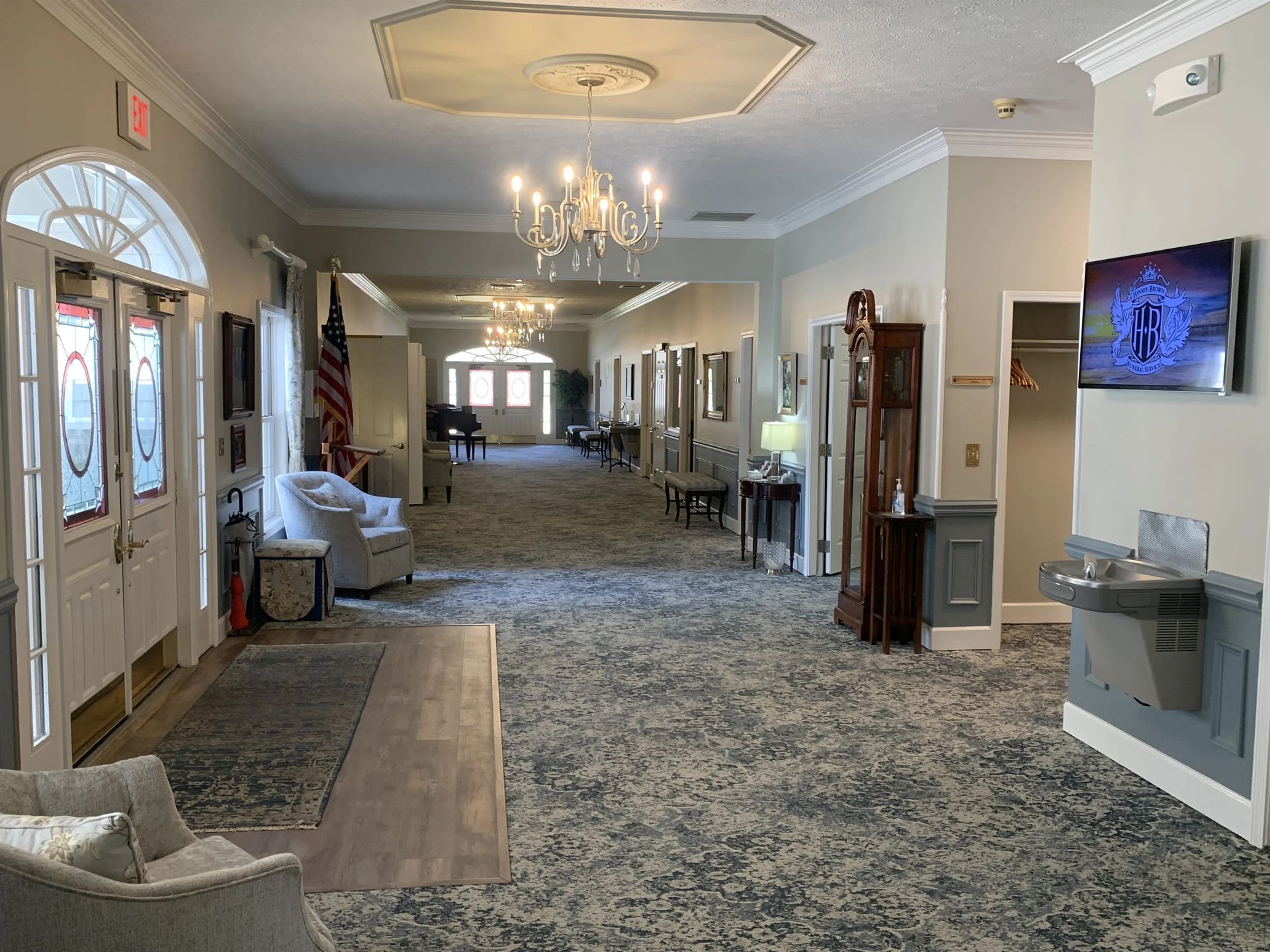 a long hallway in a building with a chandelier hanging from the ceiling .