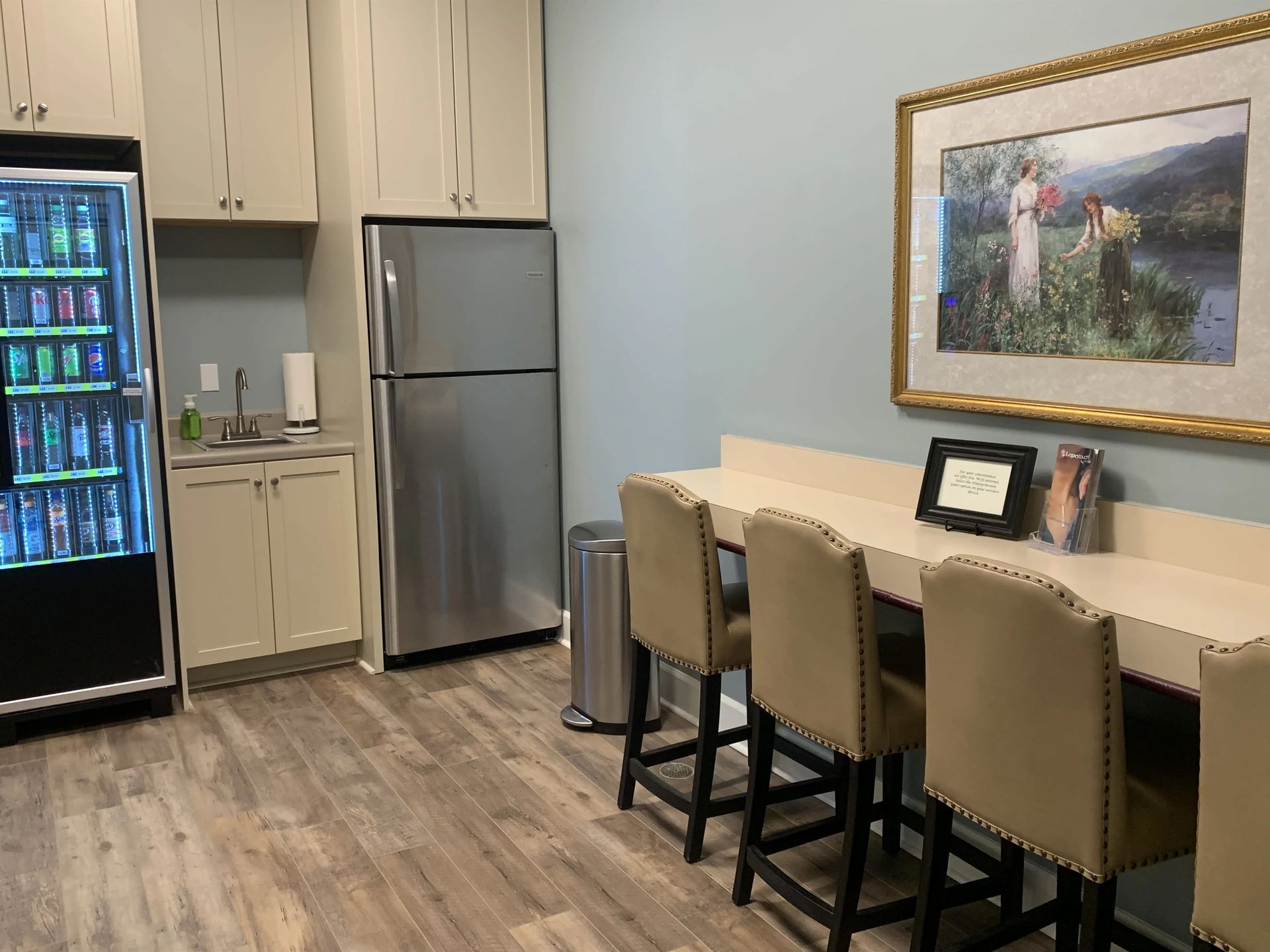 a kitchen with a refrigerator , table , chairs and a vending machine .