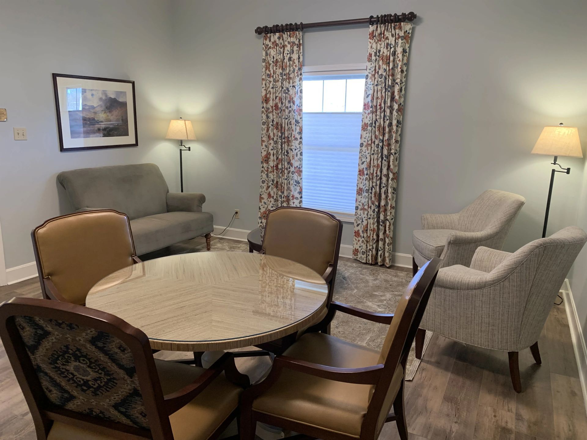 a living room with a table , chairs , a couch and a window .