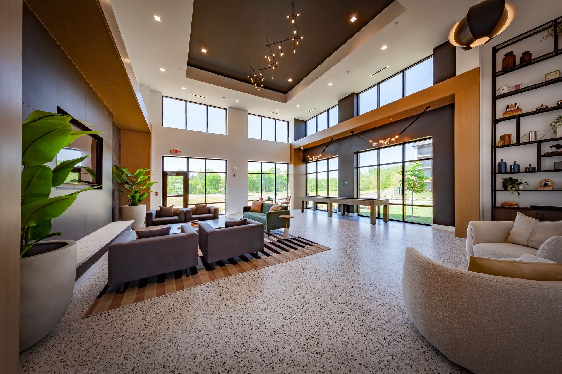 Lobby with large windows, modern furniture, and a terrazzo floor. Black, gold, and neutral colors at River Place Flats in Fishers, IN.