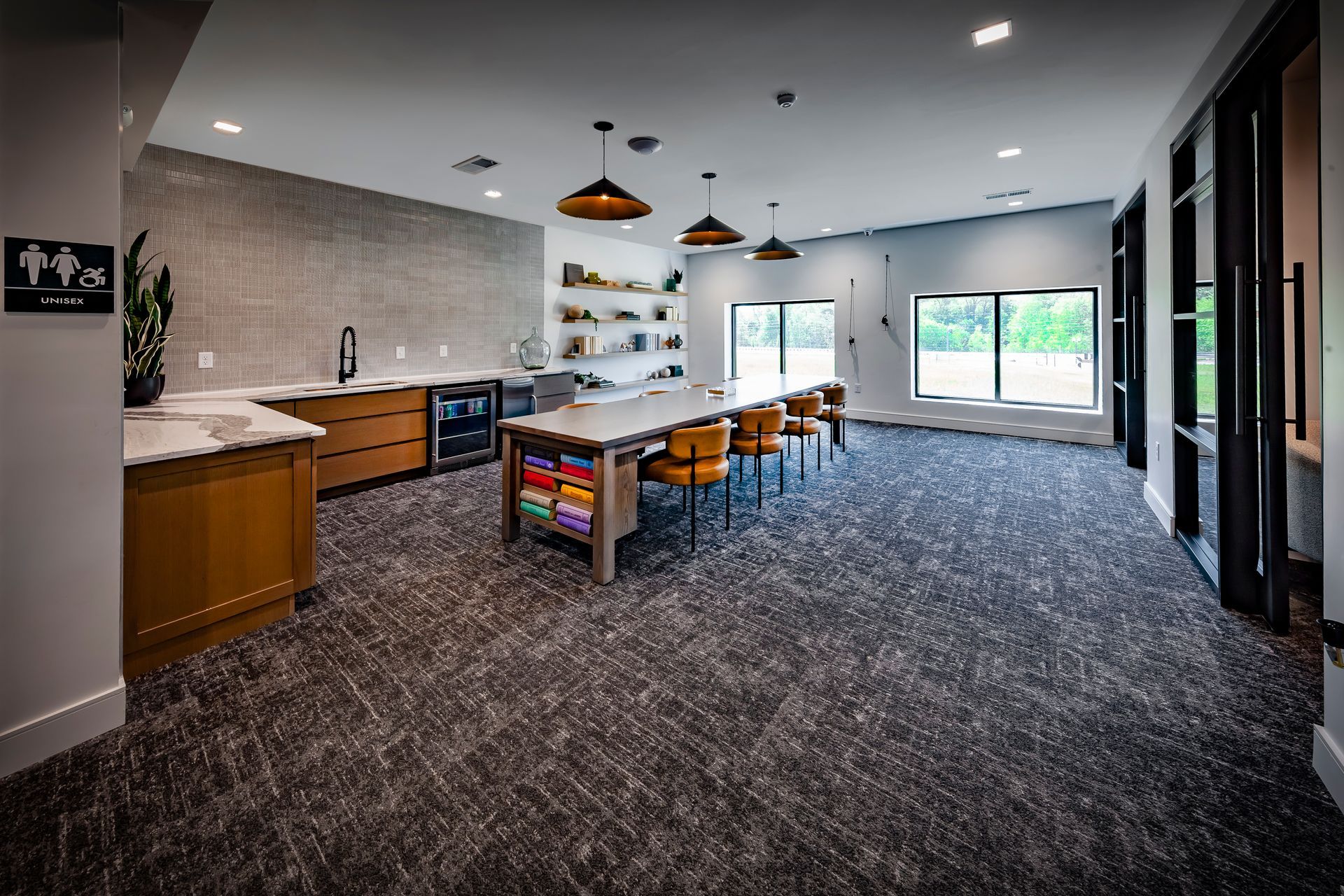 Craft room with craft table, sink, shelves, and ample natural light. Dark carpet and wooden accents at River Place Flats in Fishers, IN.