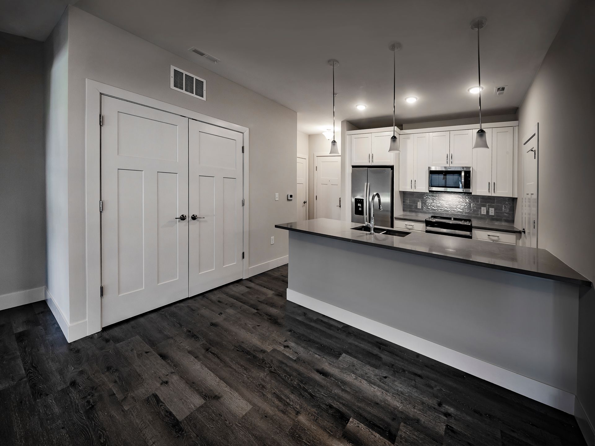 Modern kitchen with white cabinets, dark wood floor, and gray island at River Place Flats in Fishers, IN.