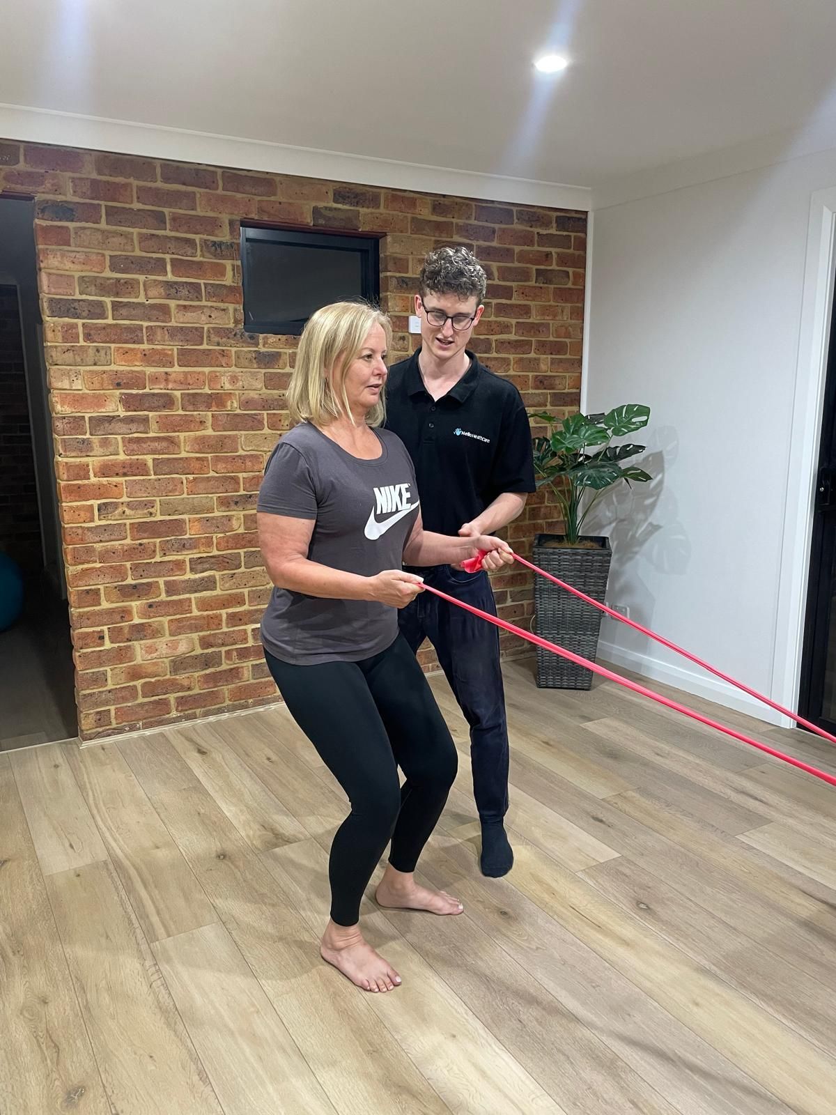 A man and a woman are doing exercises with a resistance band in a room.