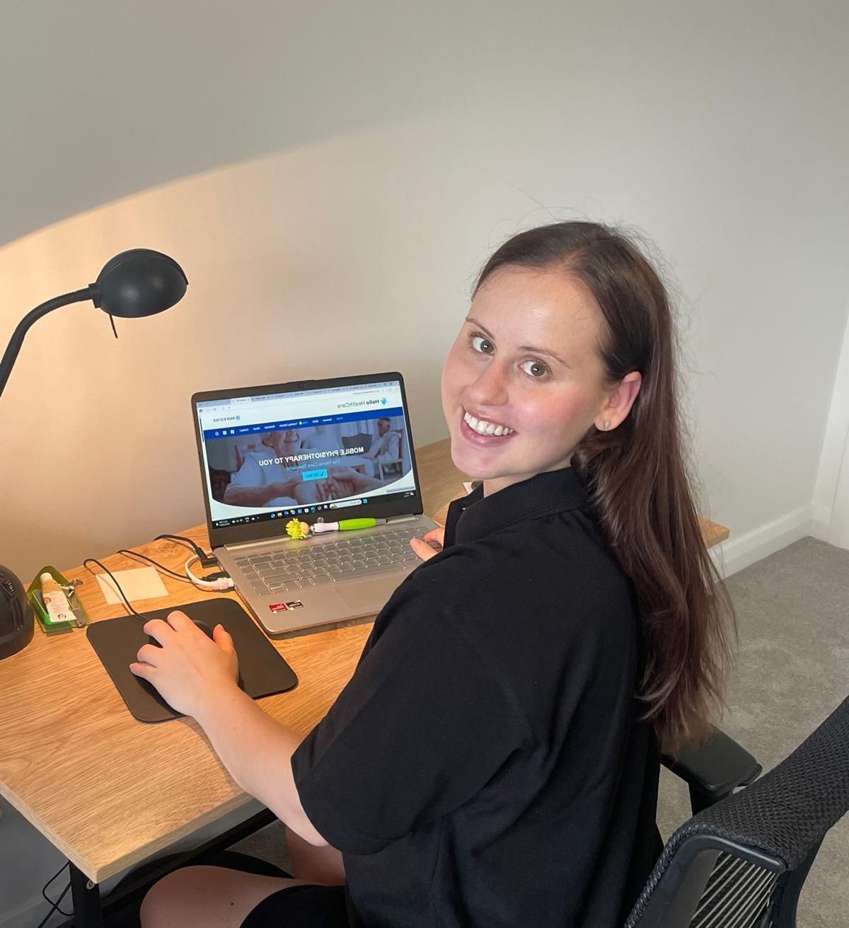 A woman is sitting at a desk with a laptop on it
