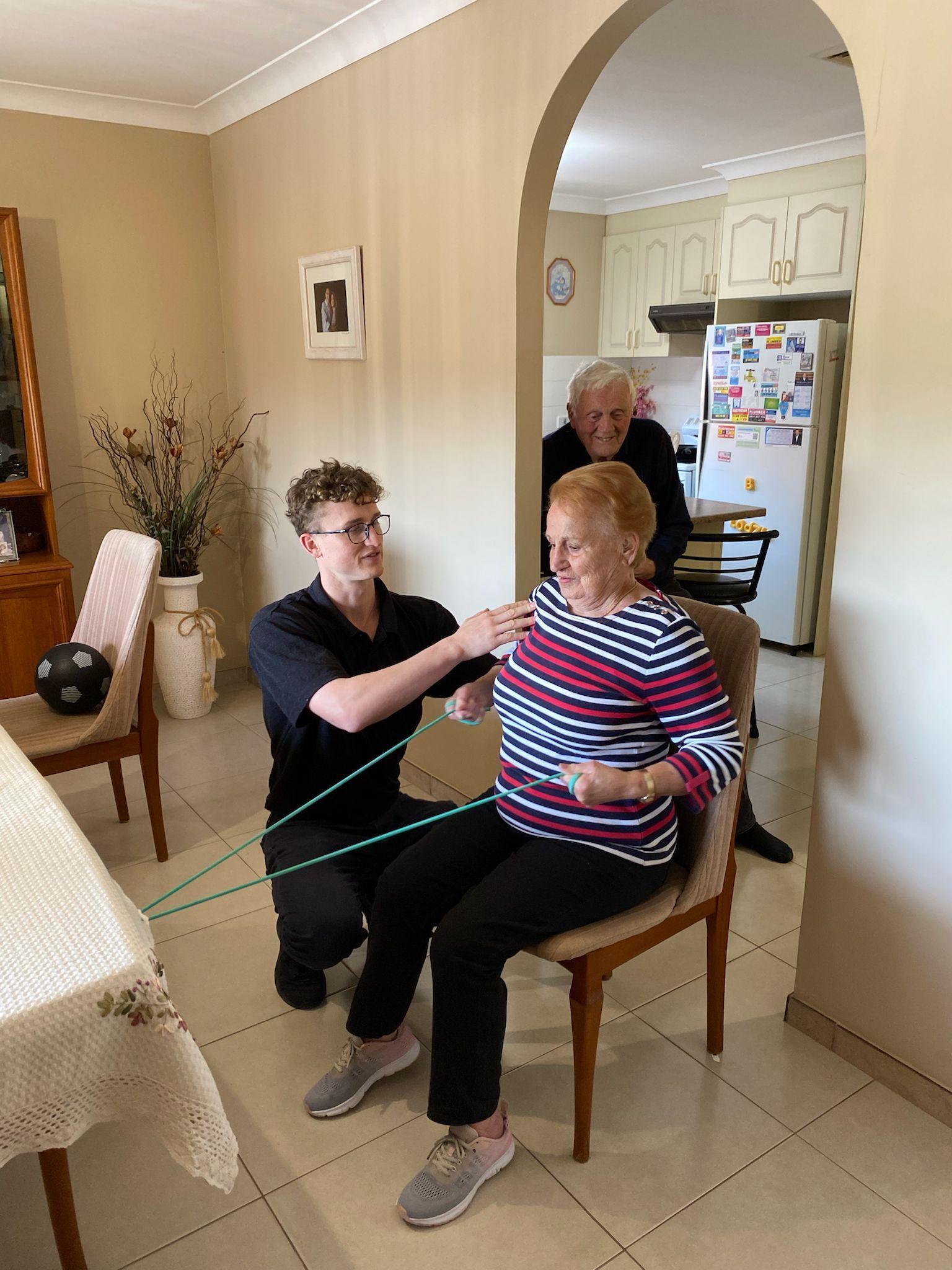 A man is kneeling down next to a woman sitting in a chair in a living room.