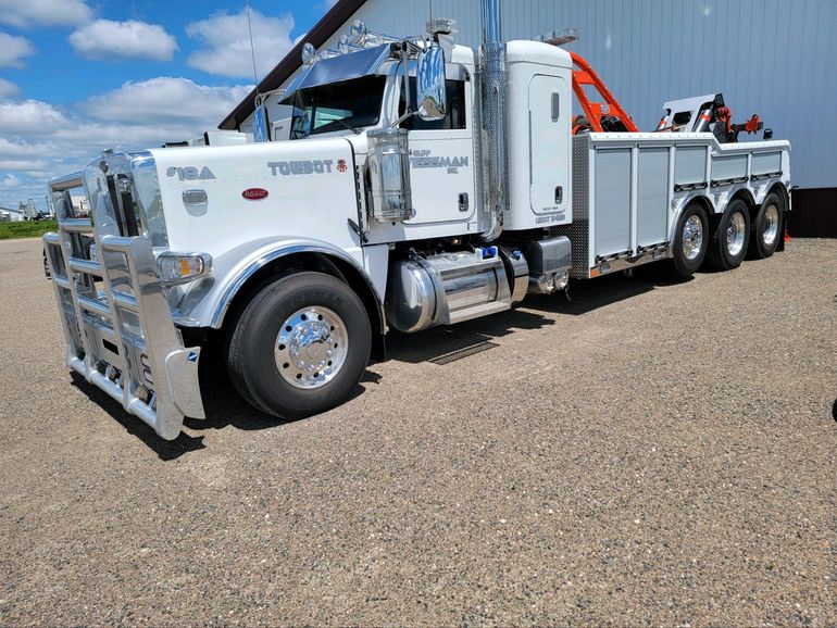 White tow truck parked outside, sunny day.