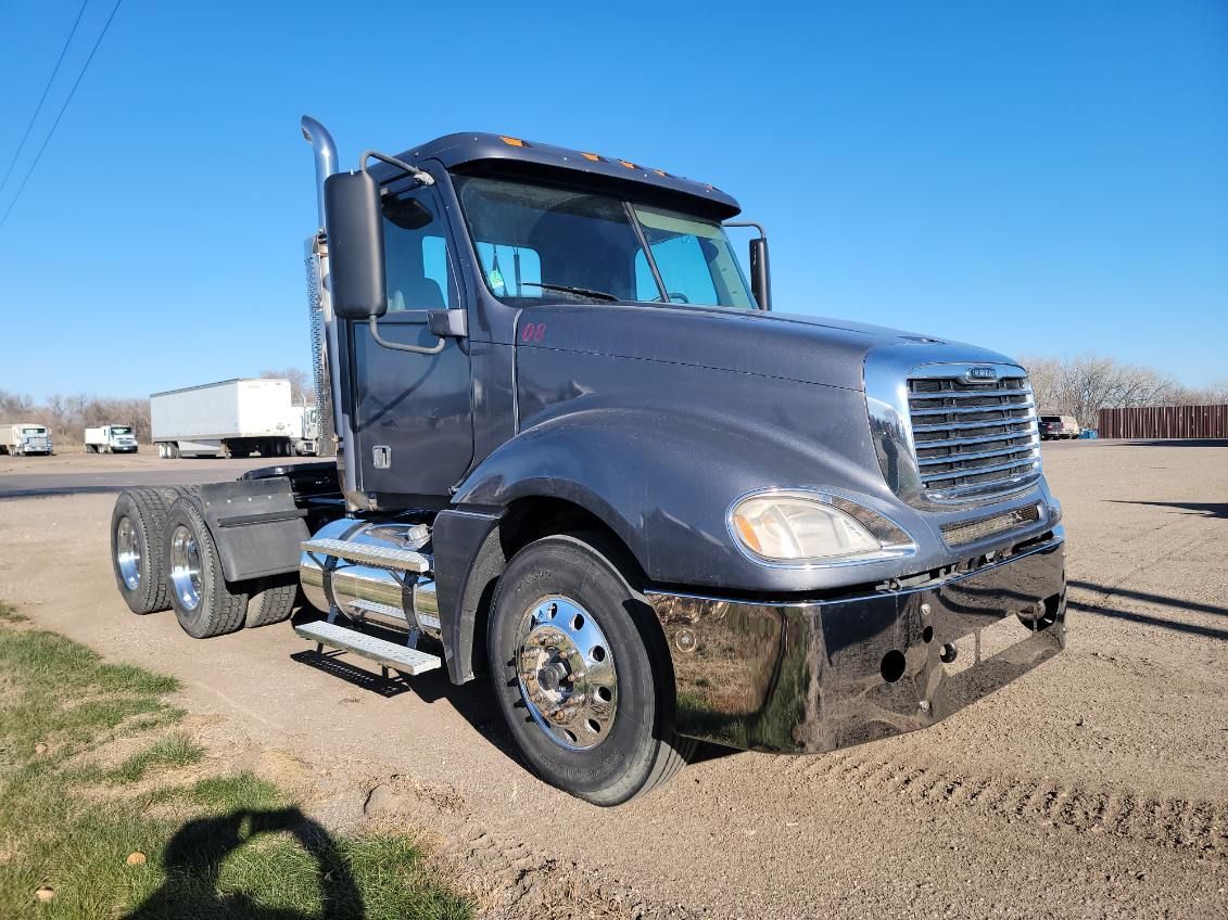 Gray semi-truck parked outdoors on a sunny day.