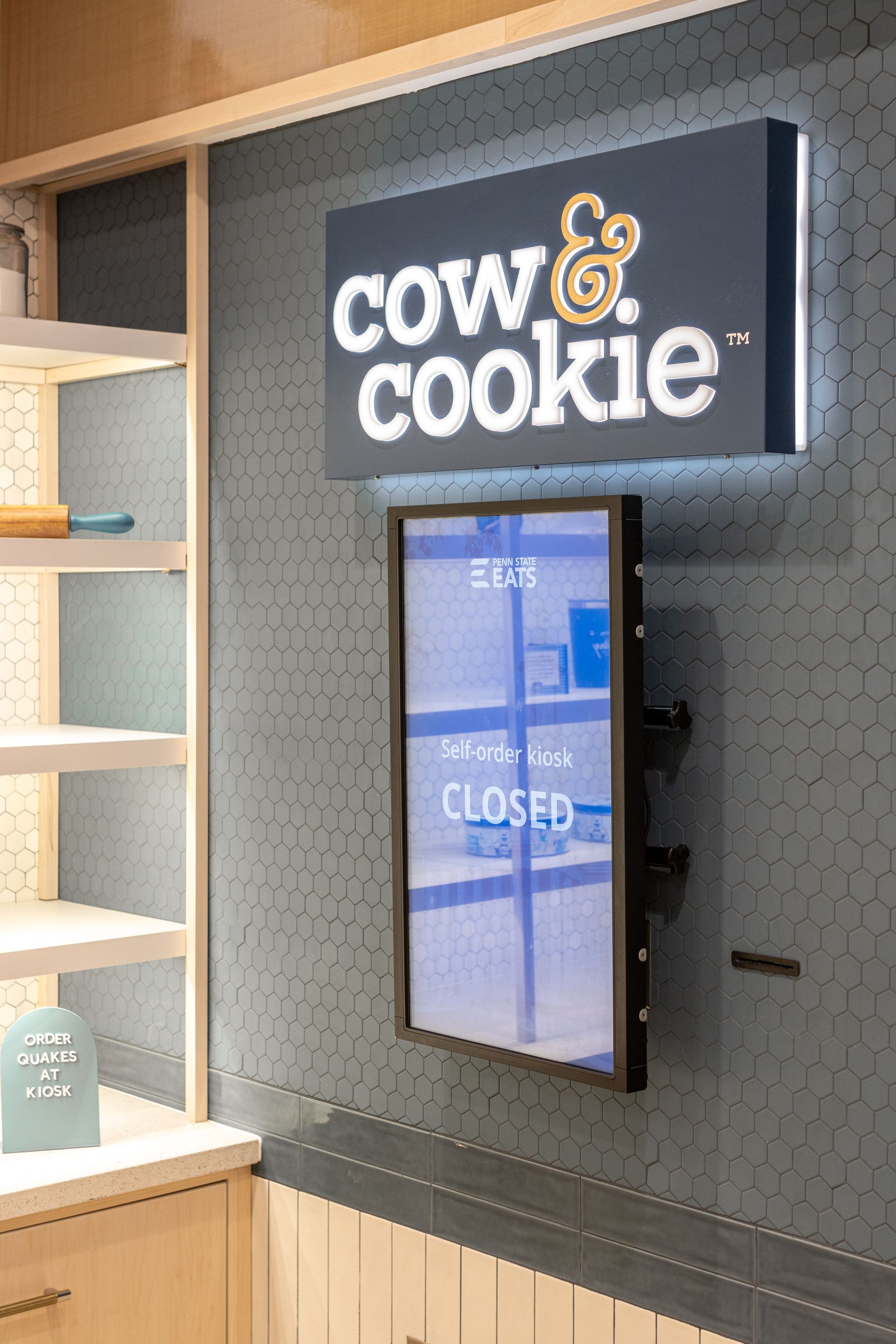 Penn State Cow & Cookie's storefront sign above a digital display reading “closed” on a gray wall