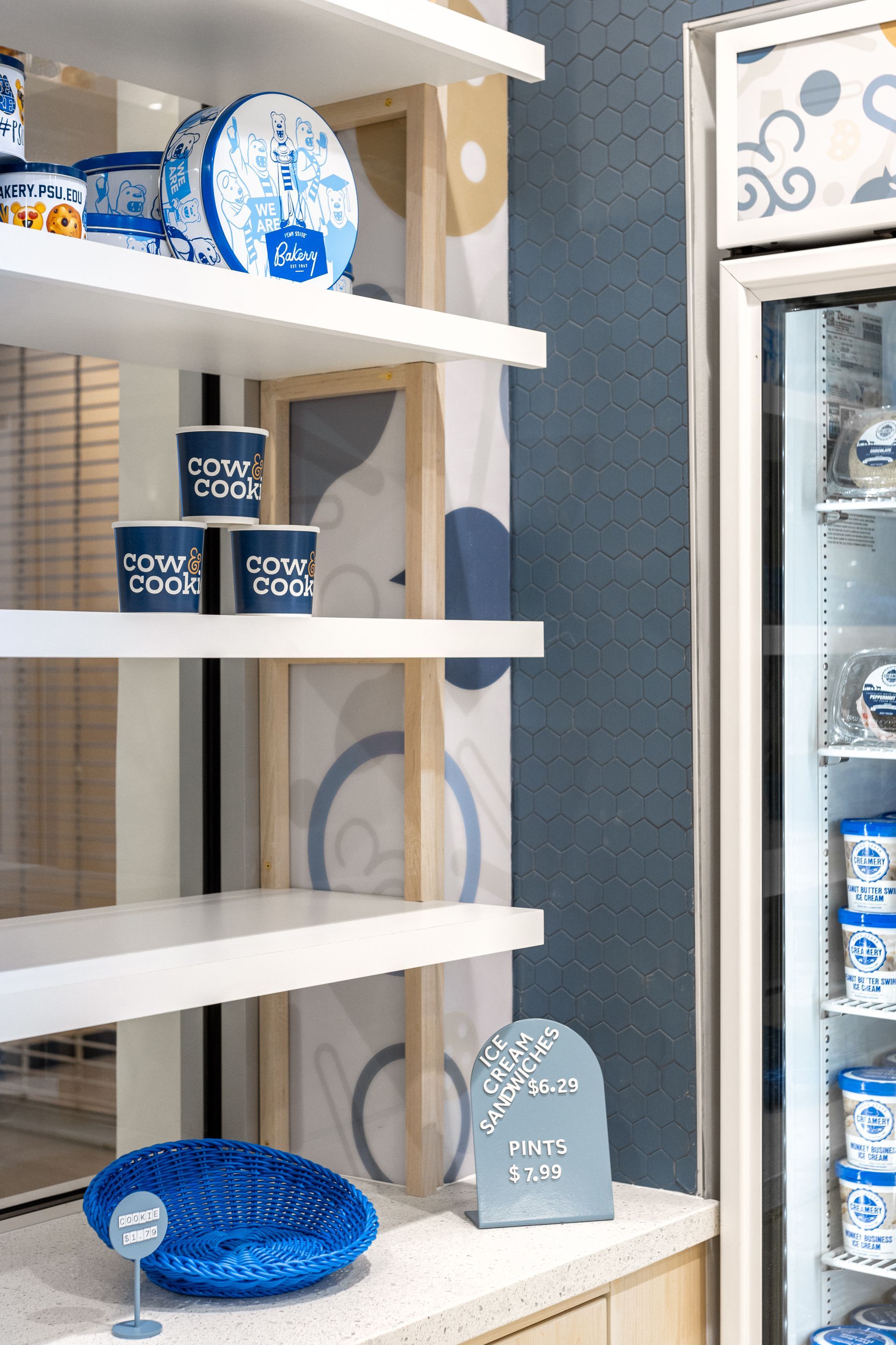 Penn State Cow & Cookie's blue-and-white ceramic decor displayed on white shelves in a bright shop interior