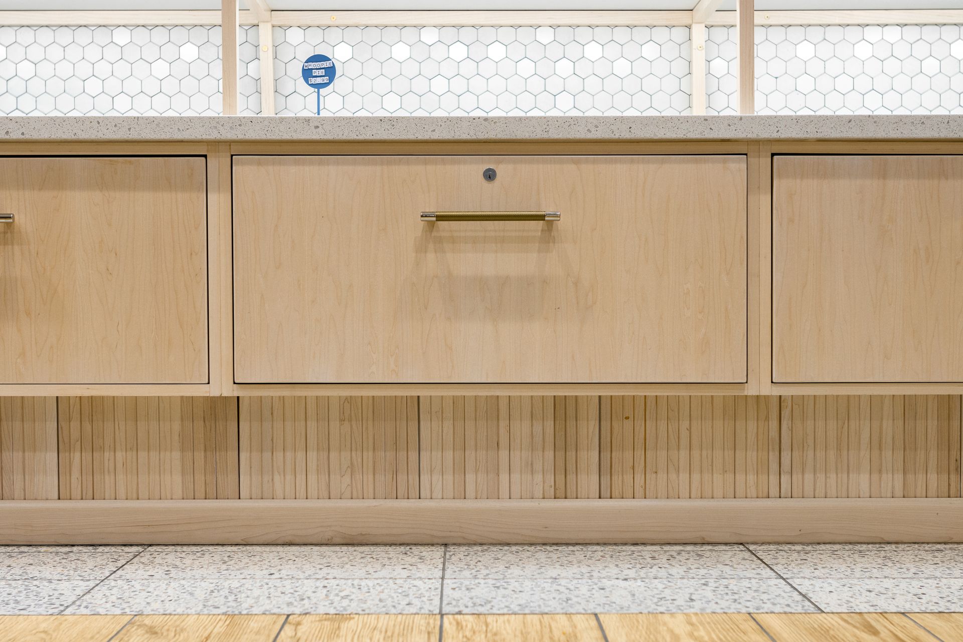 Penn State Cow & Cookie's wooden kitchen cabinets with a central drawer, woven backsplash, and tile floor.