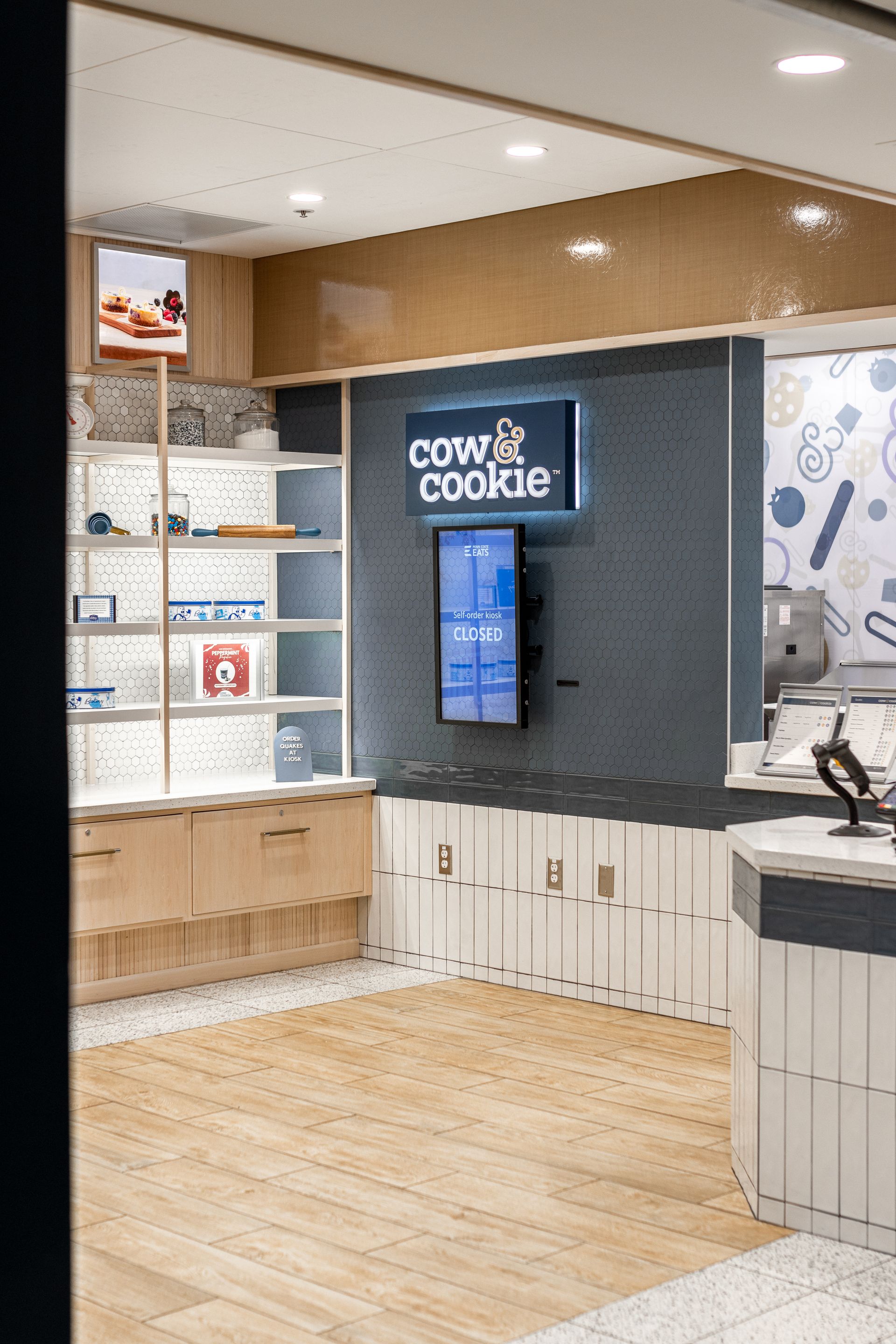 Penn State Cow & Cookie's store interior with digital menu screens, white cabinets, and light wood flooring