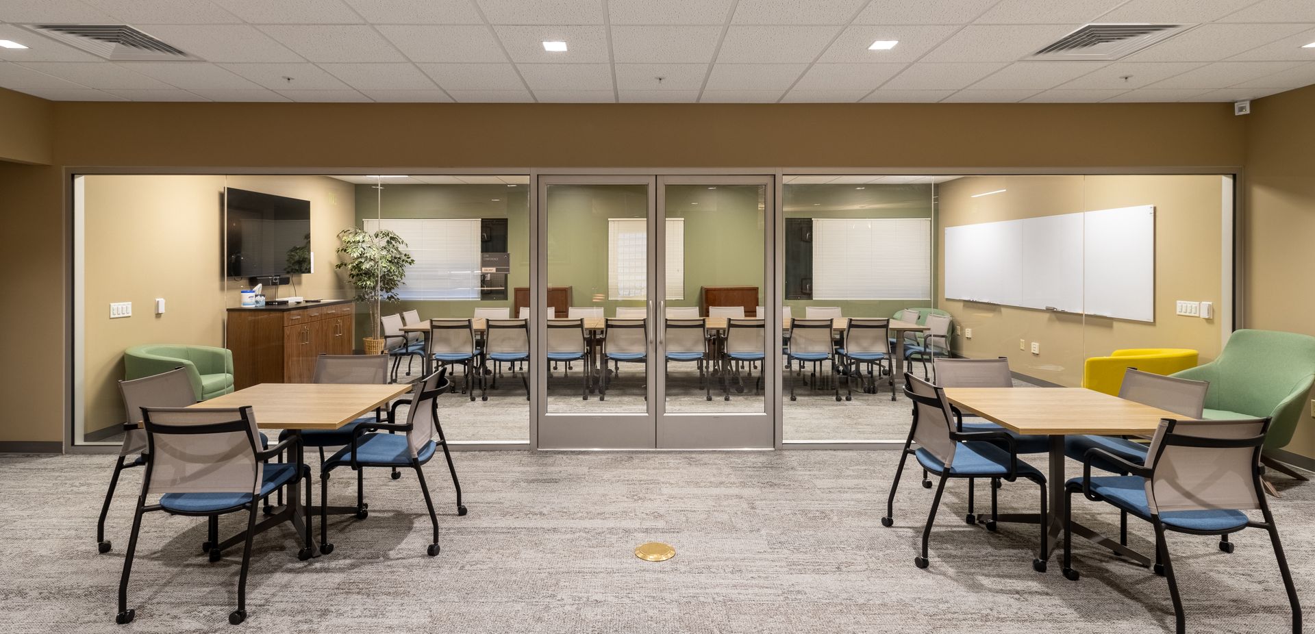 Penn State EESI Suite's empty meeting room with rows of chairs and tables facing glass doors, with laptops on the tables.