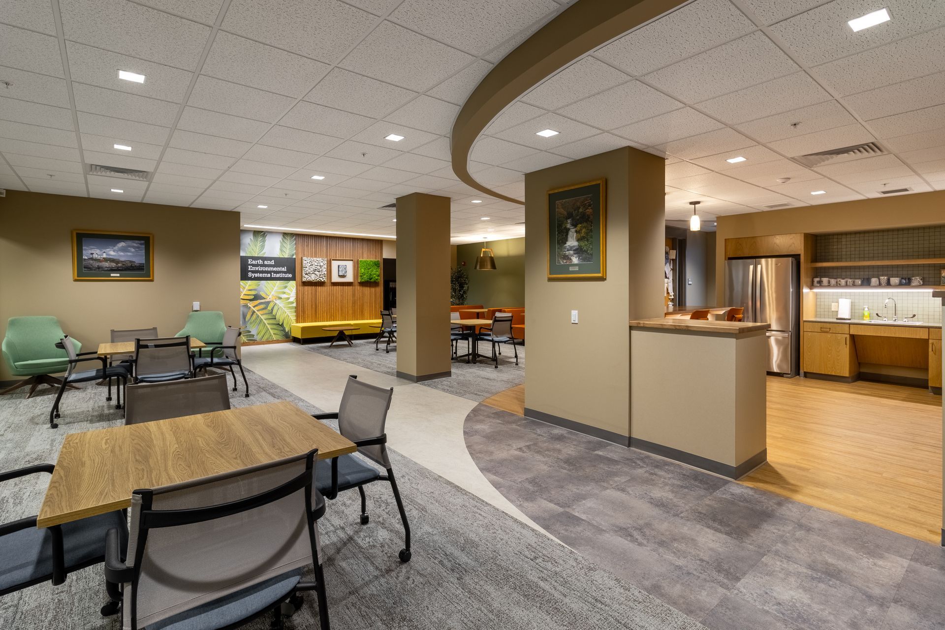 Penn State EESI Suite's modern lobby with tables, chairs, curved ceiling, and a coffee counter under warm lighting