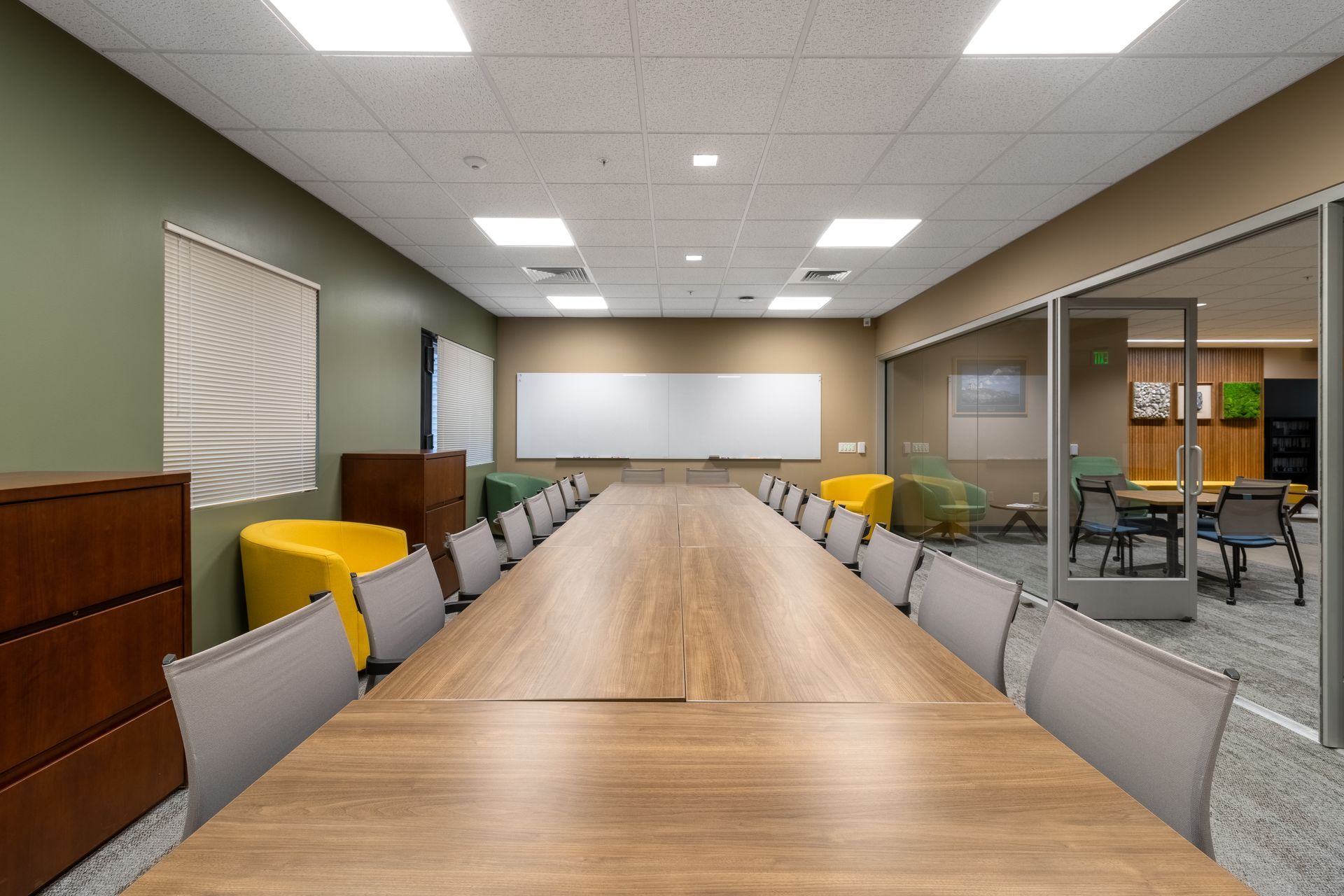 Penn State EESI Suite's modern conference room with a long wooden table, gray chairs, yellow accent chairs, and glass walls
