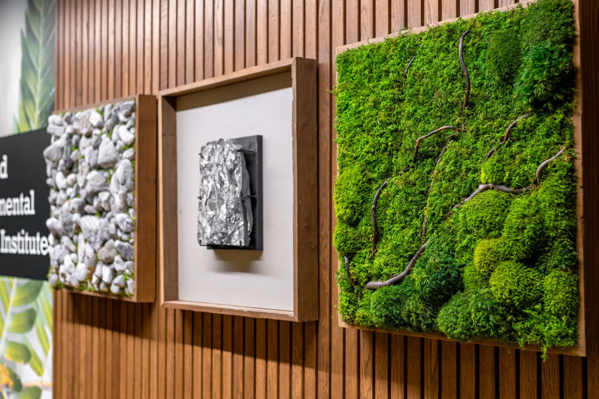 Penn State EESI Suite's wall with three square art panels: stone, metal relief, and green moss on wood slats.