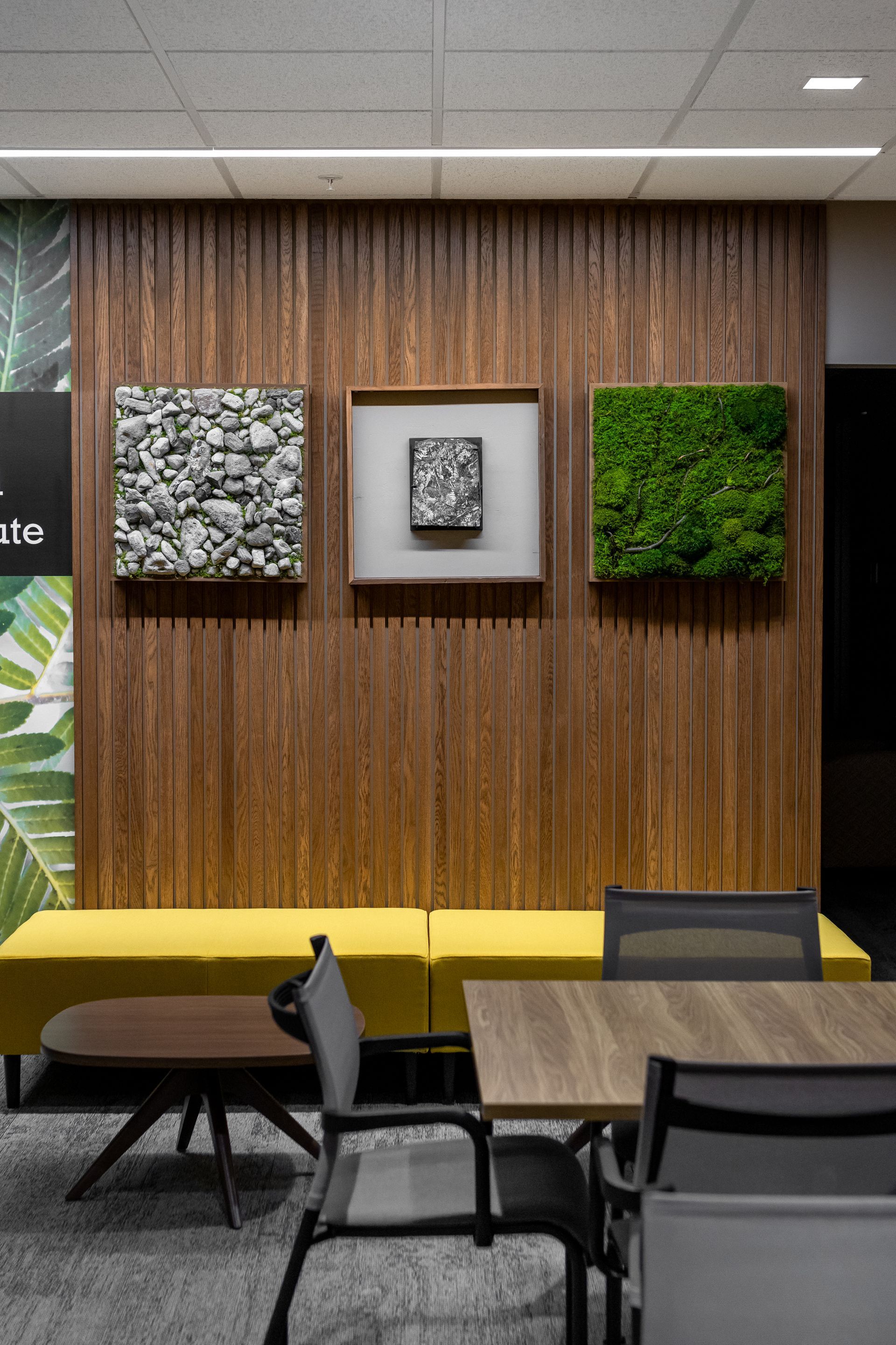 Penn State EESI Suite's modern lounge with wood wall, yellow banquette, and three framed wall art panels