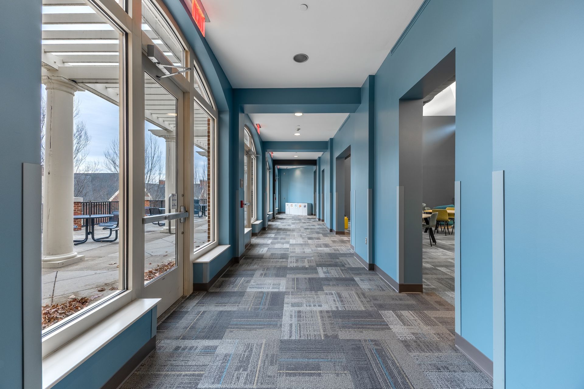 Eastview Terrace Kitchen's bright hallway with blue walls, large windows, and patterned carpet in a modern building