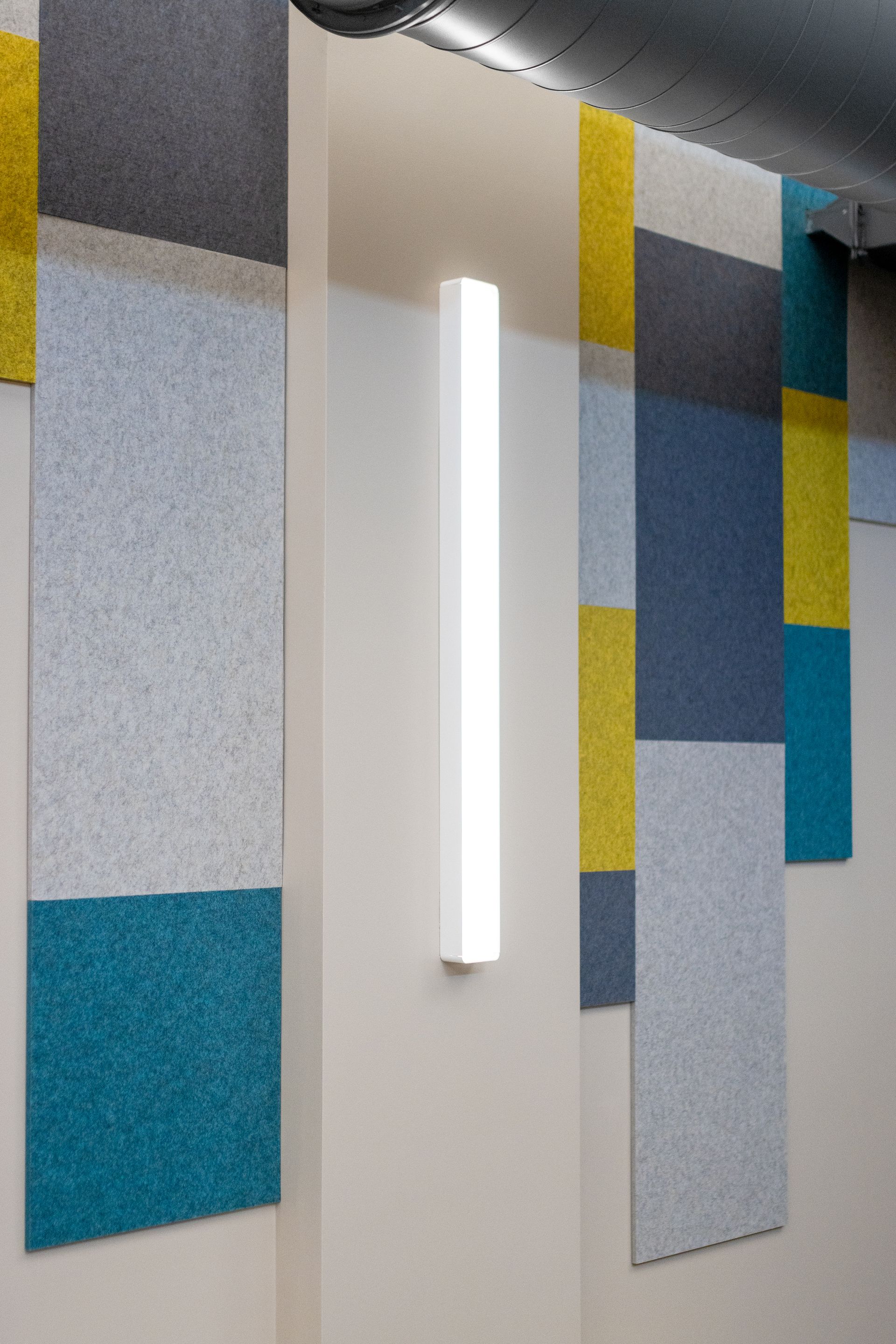Eastview Terrace Kitchen's colorful geometric wall panels with a vertical white light fixture in a modern interior corridor