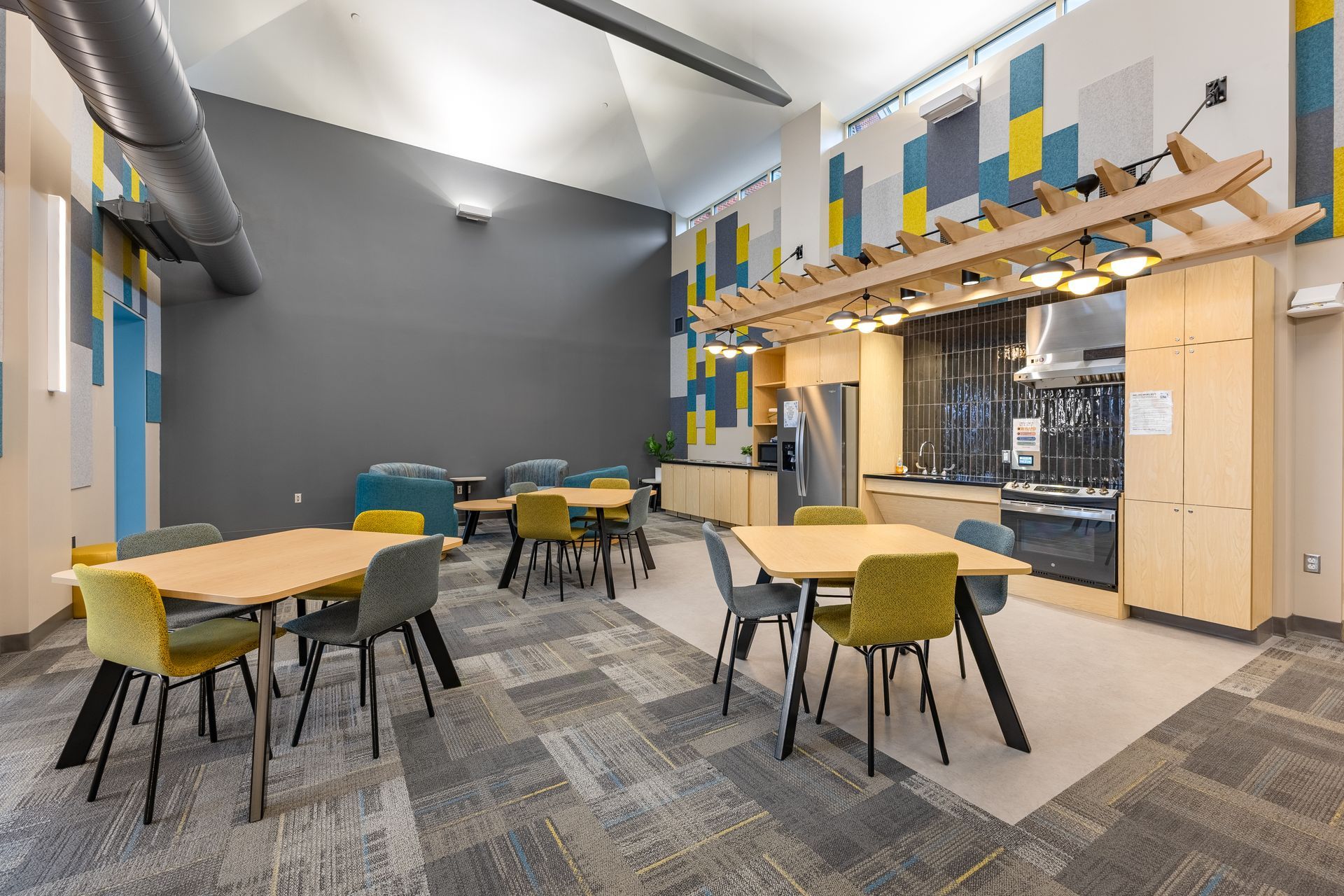Eastview Terrace Kitchen's modern office lounge with round tables, green chairs, gray carpet, and wood accents