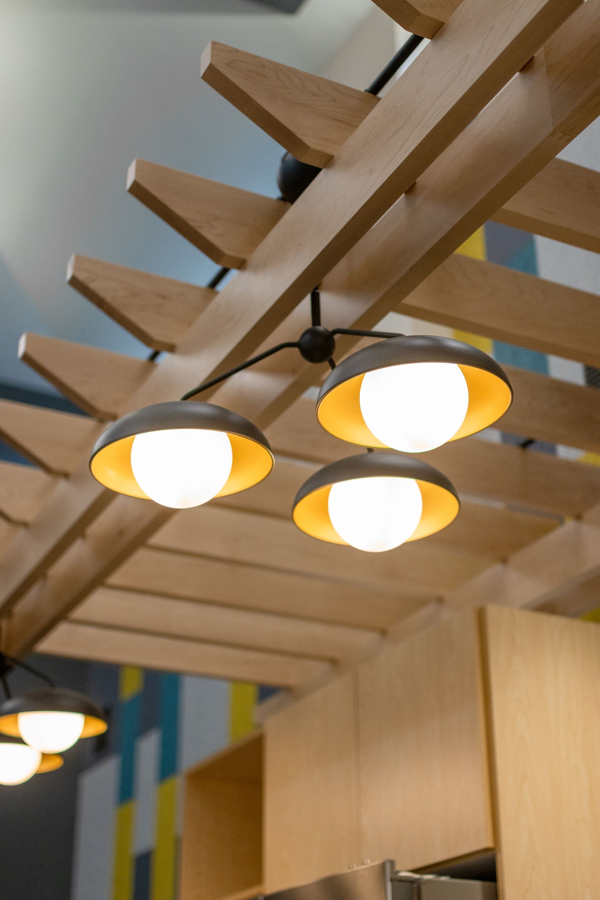 Eastview Terrace Kitchen's warm pendant lights hang beneath wooden ceiling beams in a modern interior.