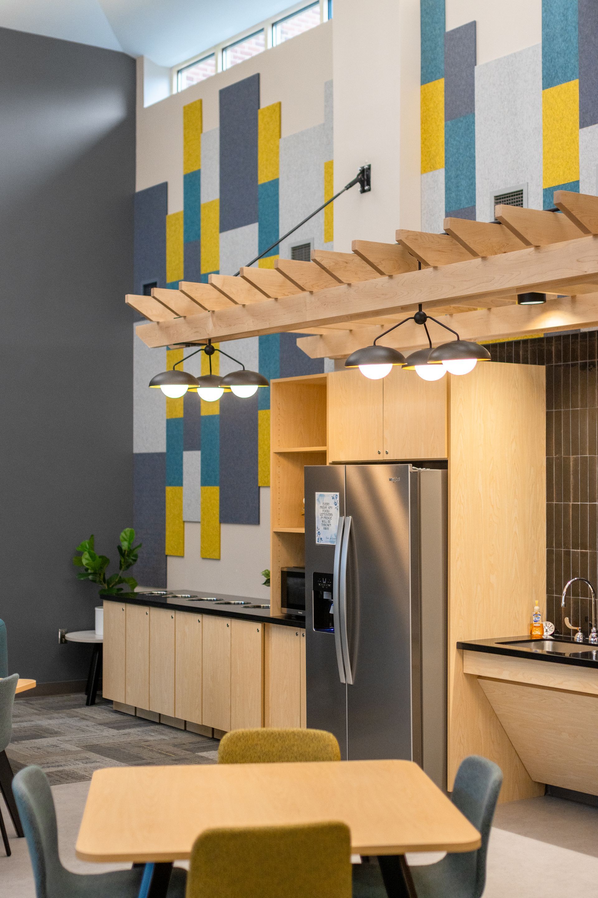 Eastview Terrace Kitchen's modern kitchen-dining area with wood table, pendant lights, stainless fridge, and colorful tiled wall