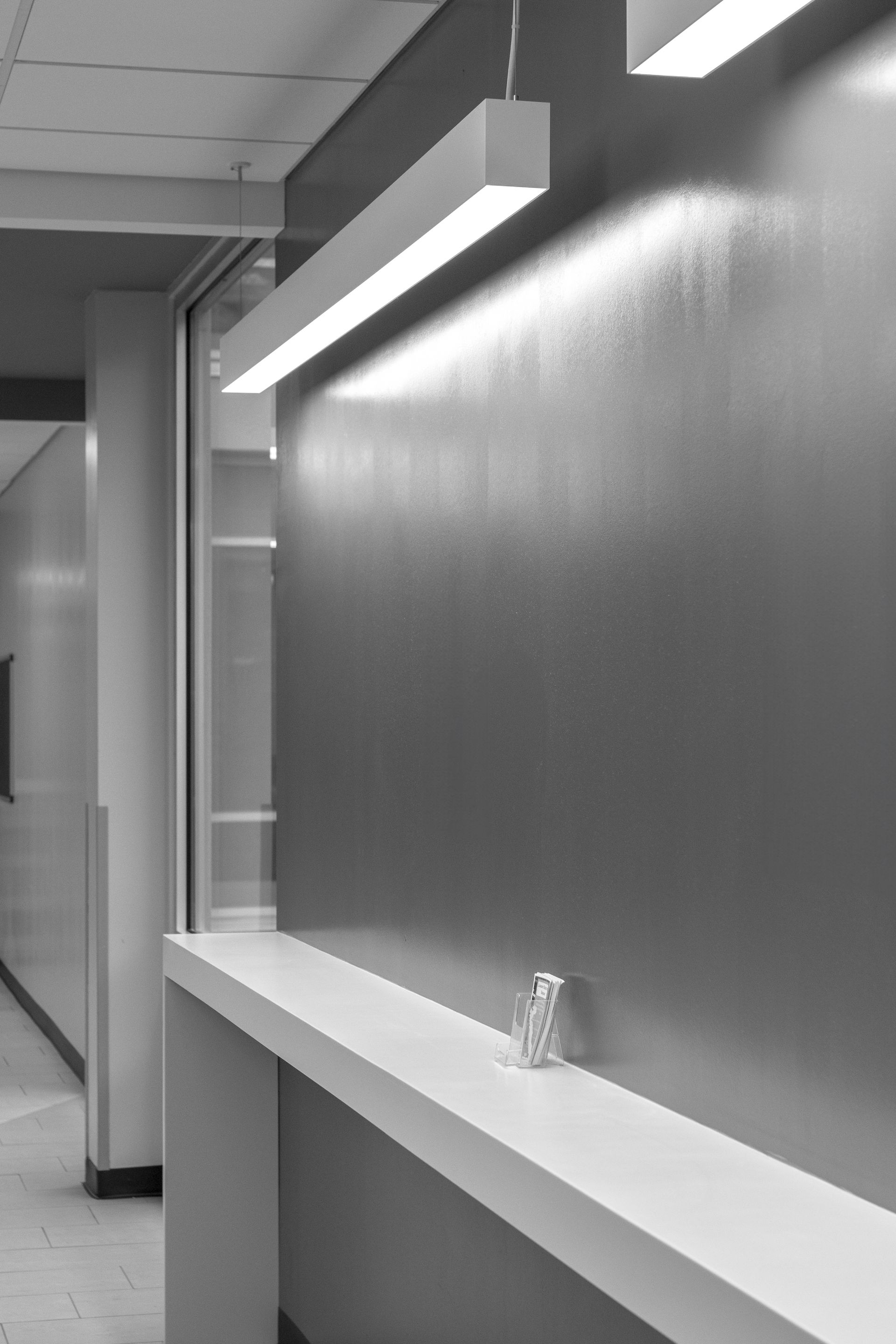 A modern hallway with a built-in shelf, overhead lighting, and a small object on the shelf.