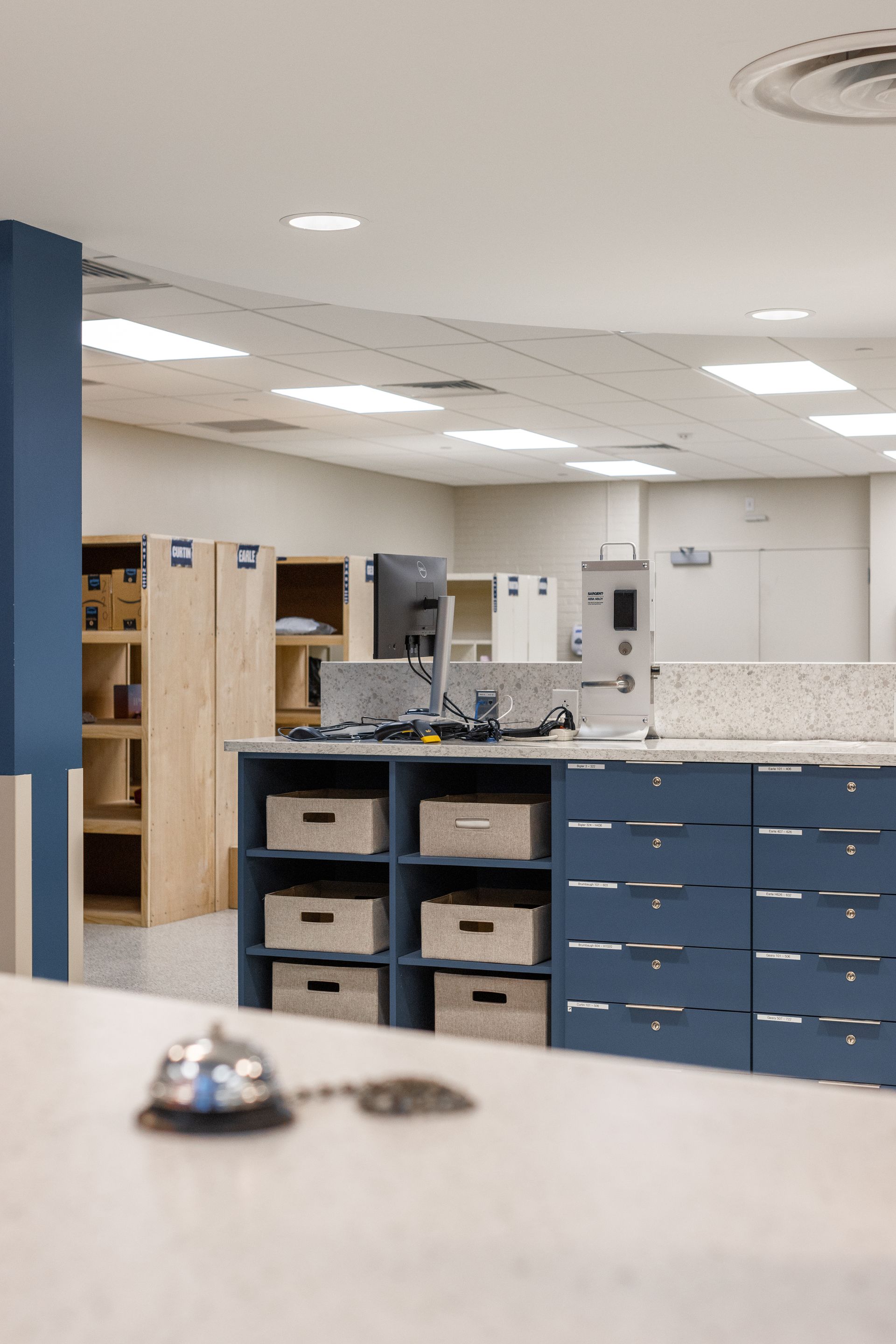 A counter with a service bell in a room with built-in storage and overhead lighting.