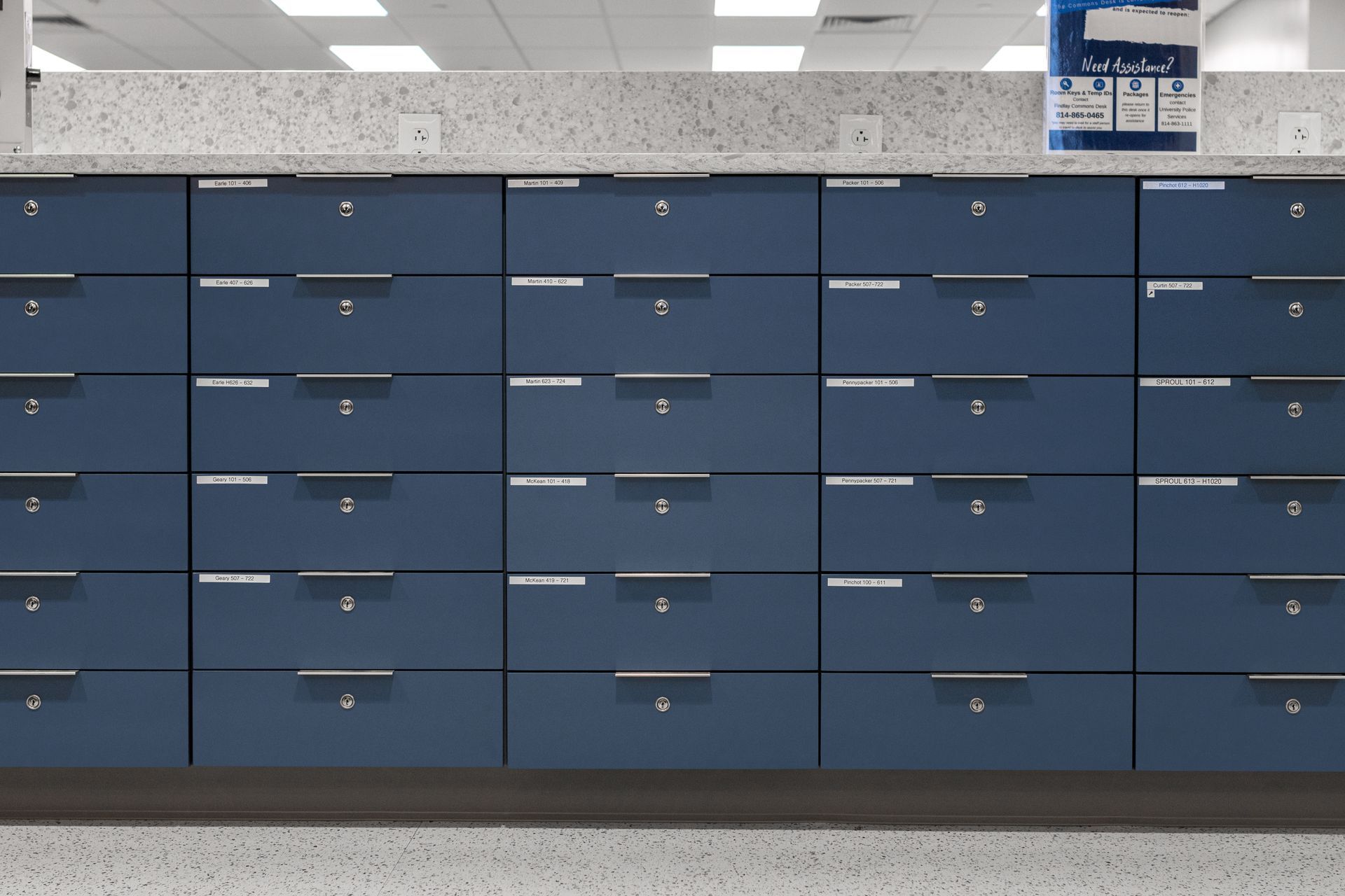 Rows of blue mailboxes with silver handles in a brightly lit room.