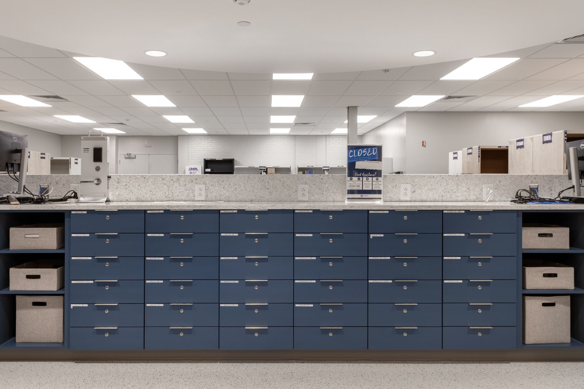 Blue drawers with labels behind a counter. Fluorescent lighting in ceiling.