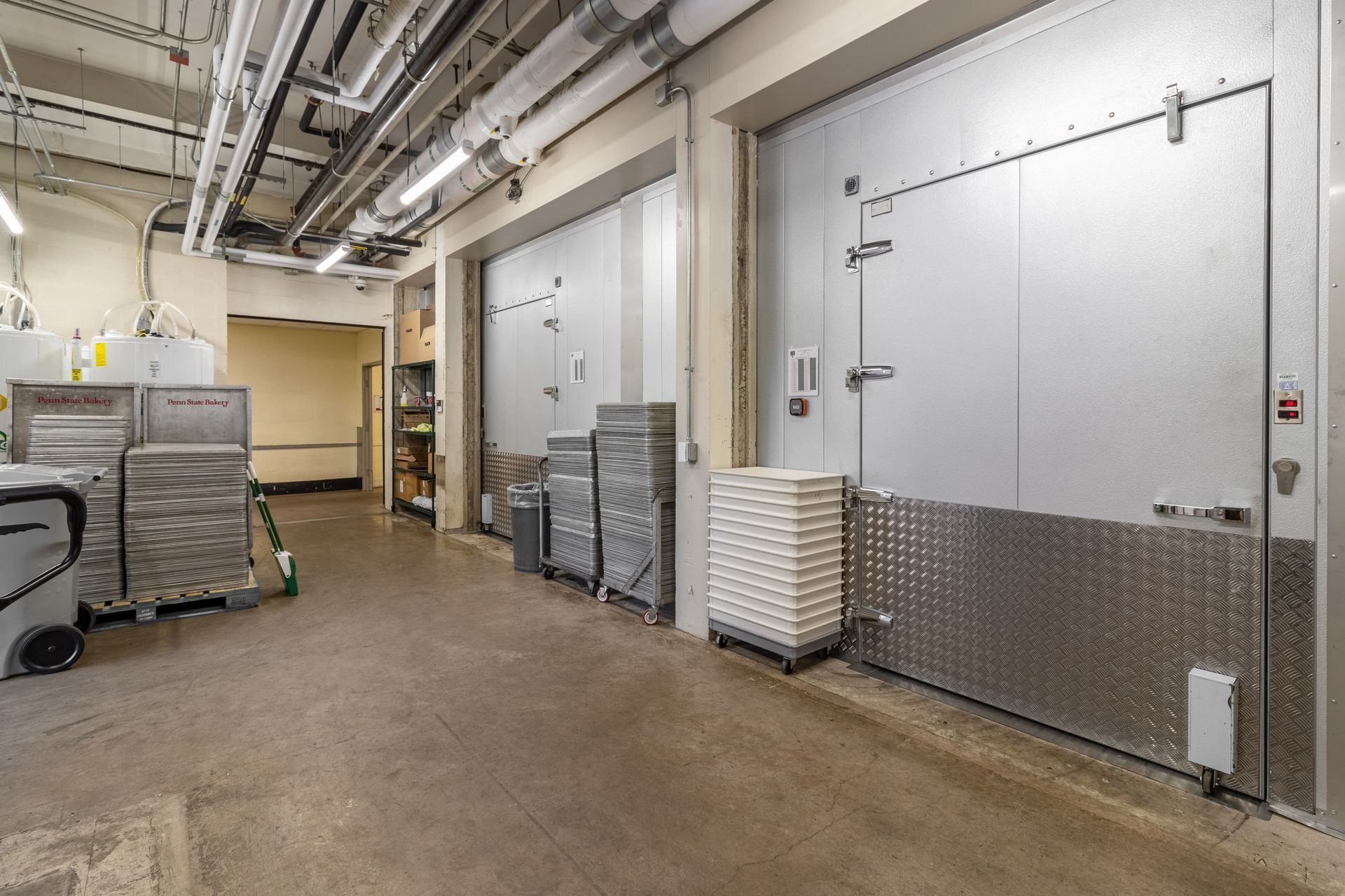 Cooler storage room with large metal doors, carts, and equipment.