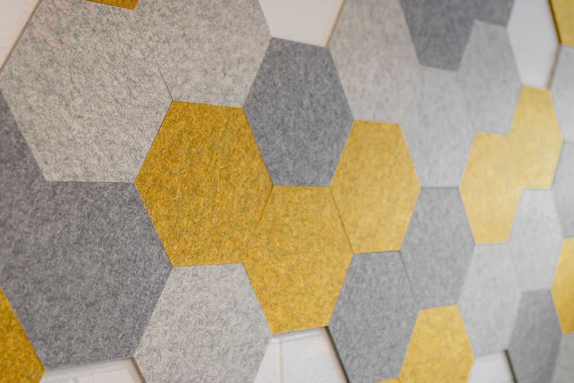 Hexagonal sound-absorbing wall panels in shades of grey and gold.