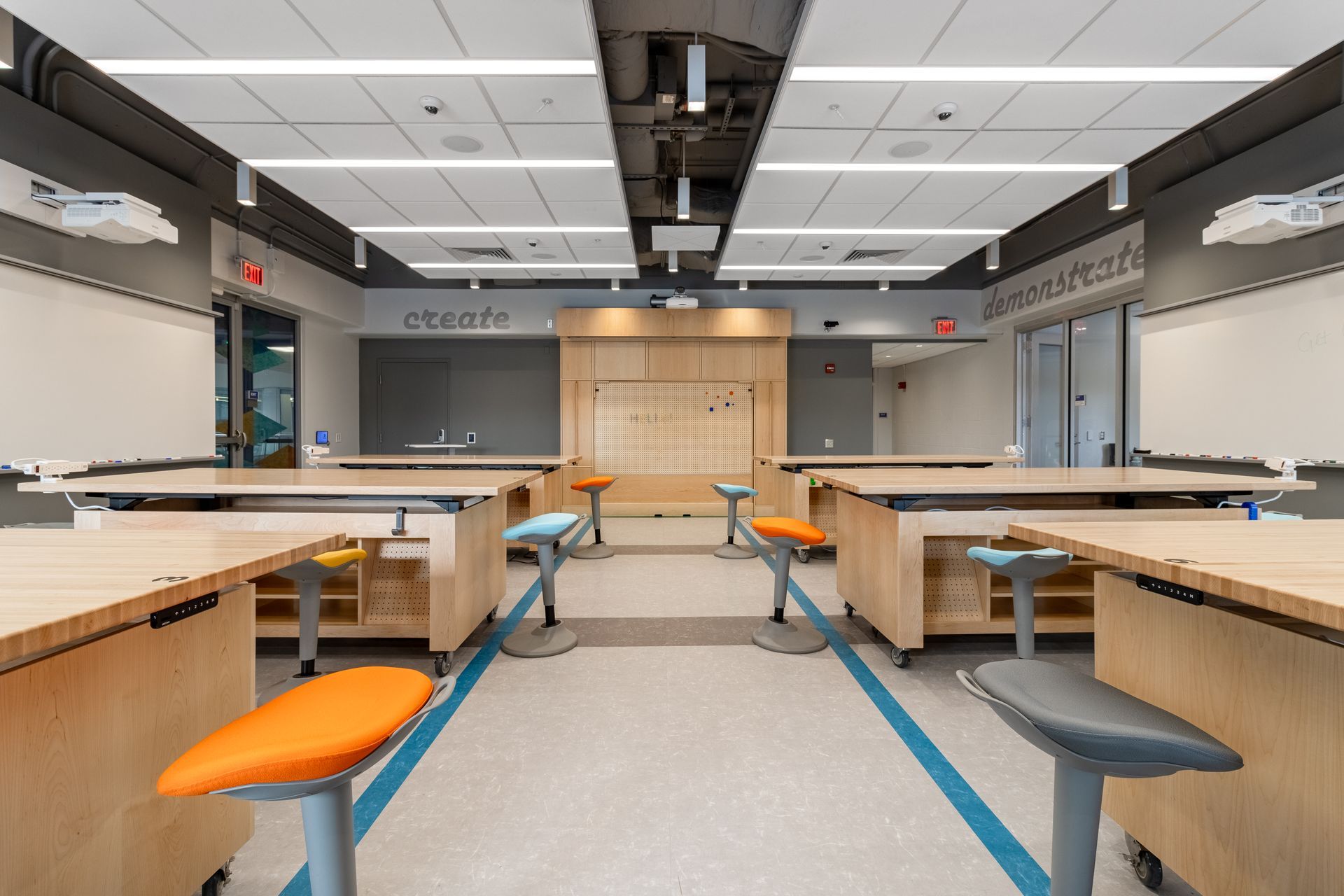 Modern classroom with wooden desks and colorful stools.