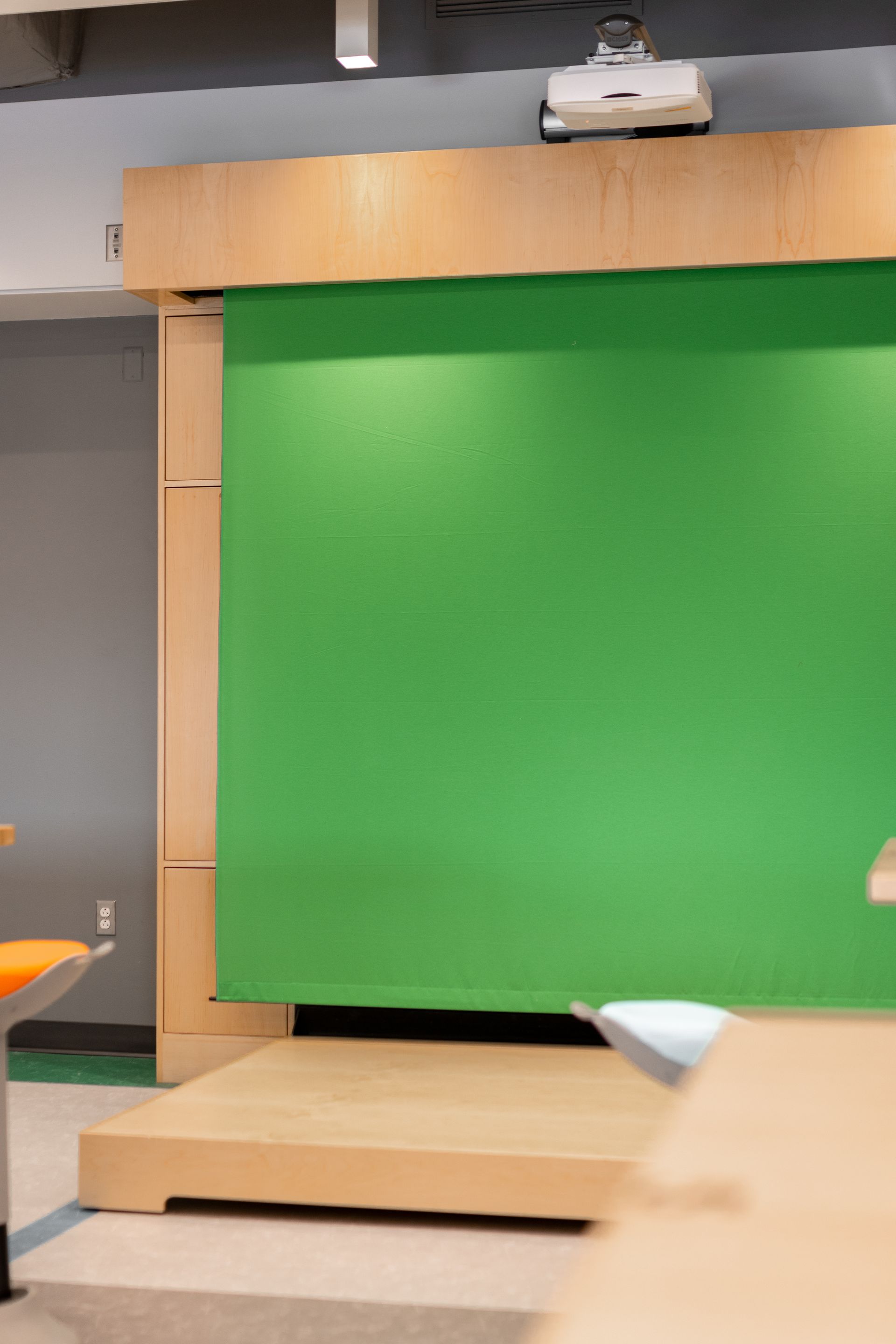 Green screen backdrop in a studio setting, with a projector mounted above.