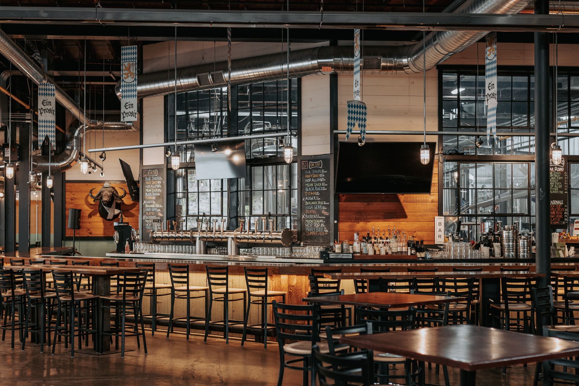 Axemann Brewery's interior with long wooden counter, high stools, and large windows