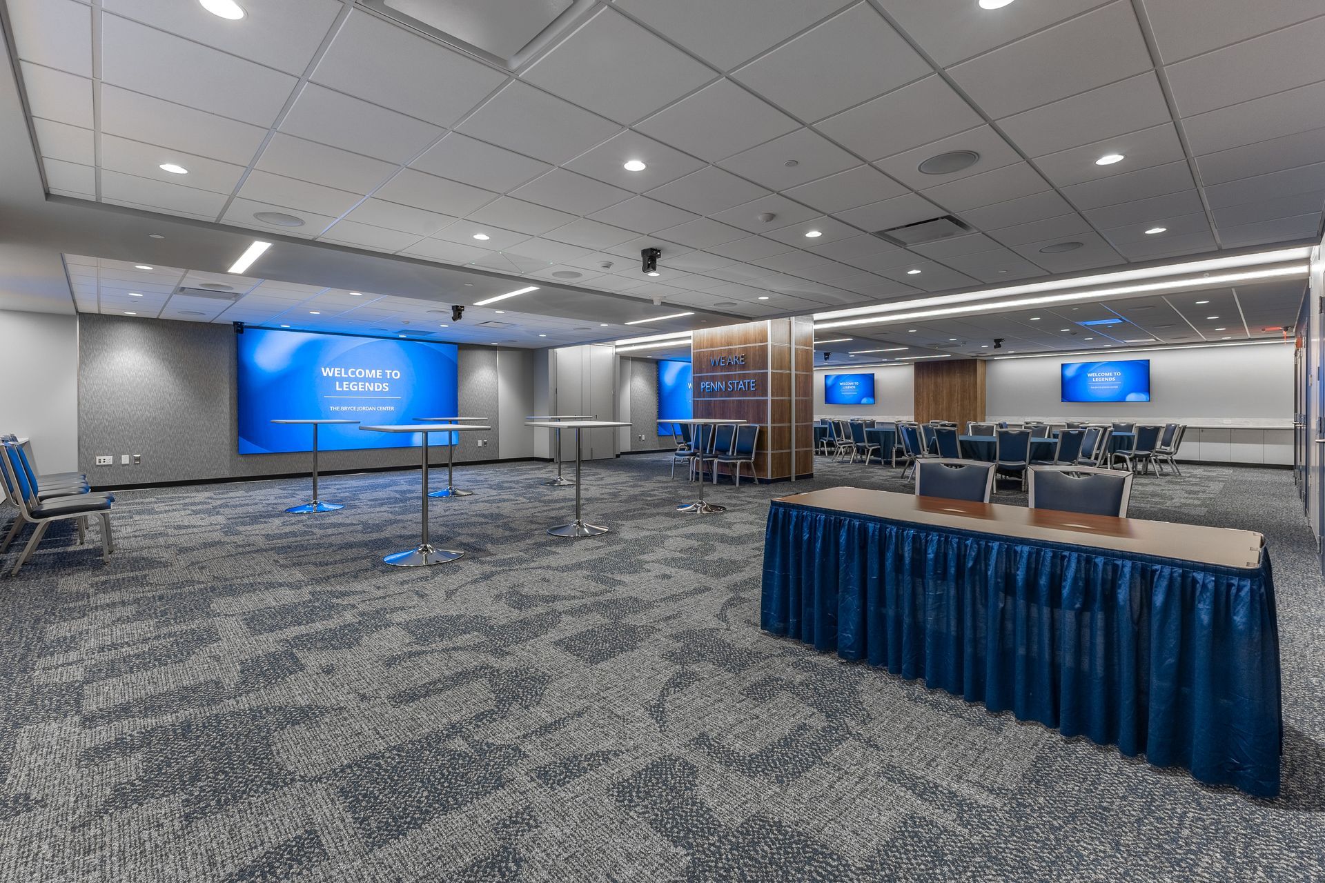 Bryce Jordan Center's empty conference room with blue presentation screens and rows of chairs around a long table