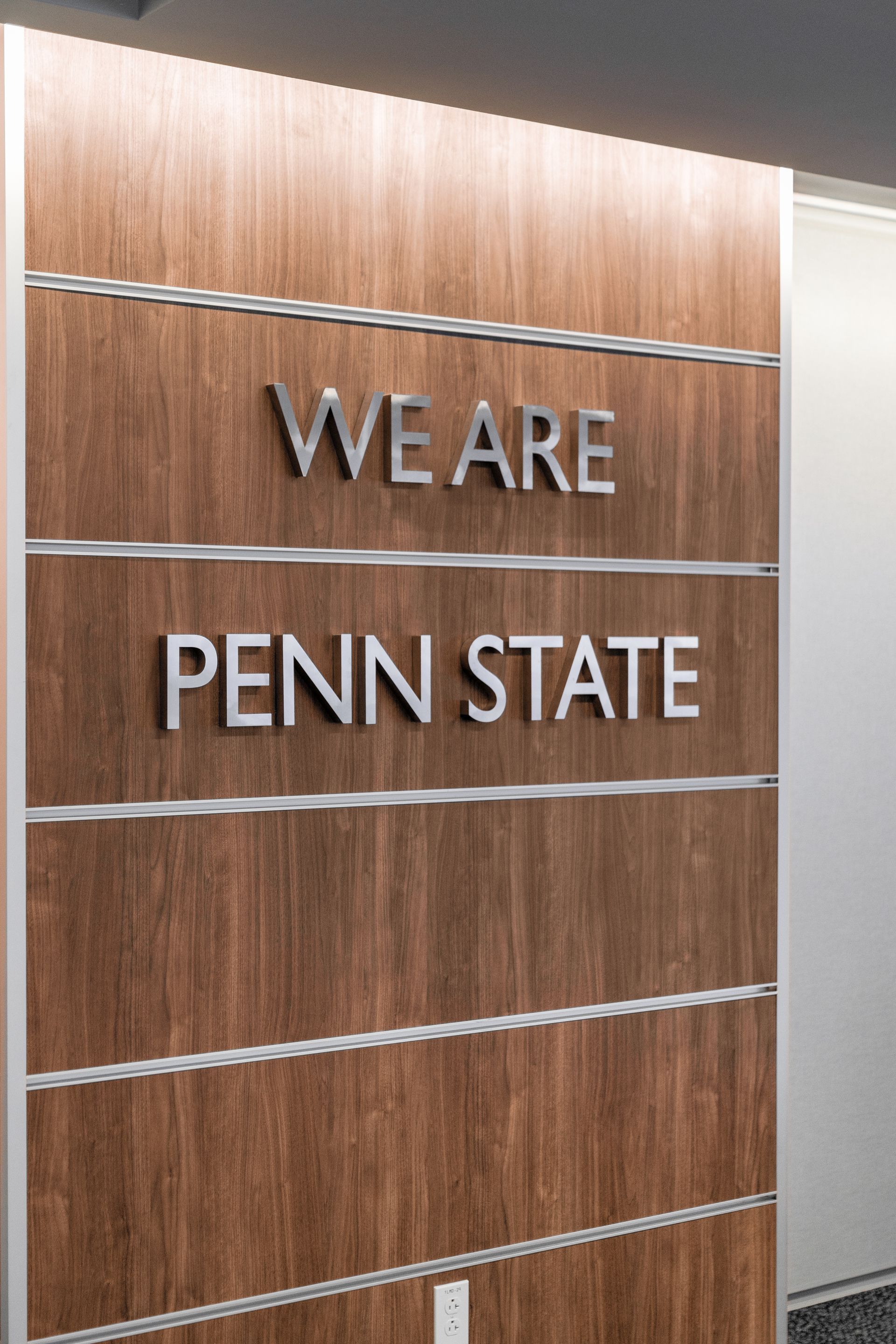 Bryce Jordan Center's wood-paneled wall with metal letters reading “WE ARE PENN STATE”