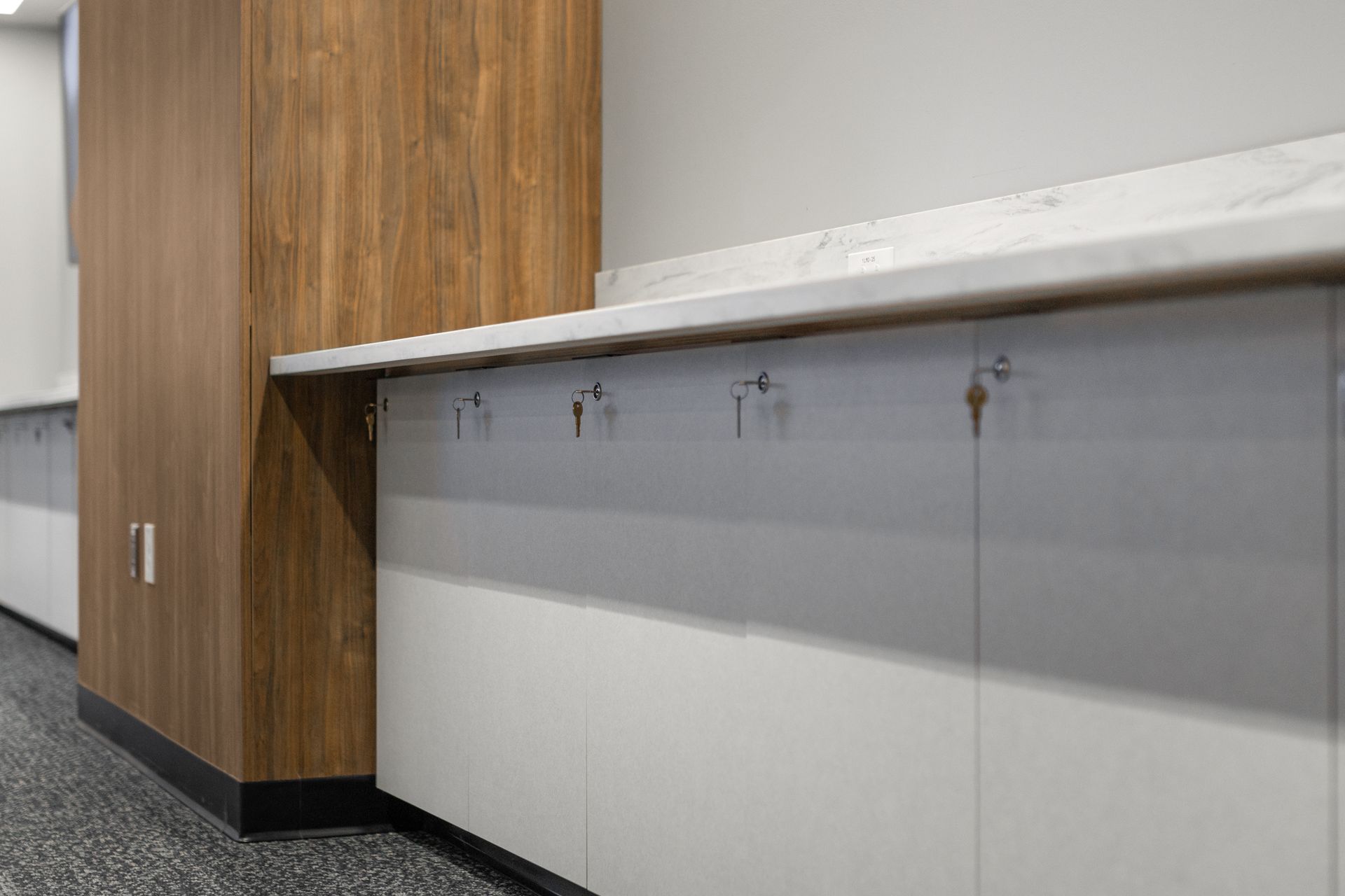 Bryce Jordan Center's empty office hallway with wood-paneled column and a row of wall-mounted hooks along a white wall