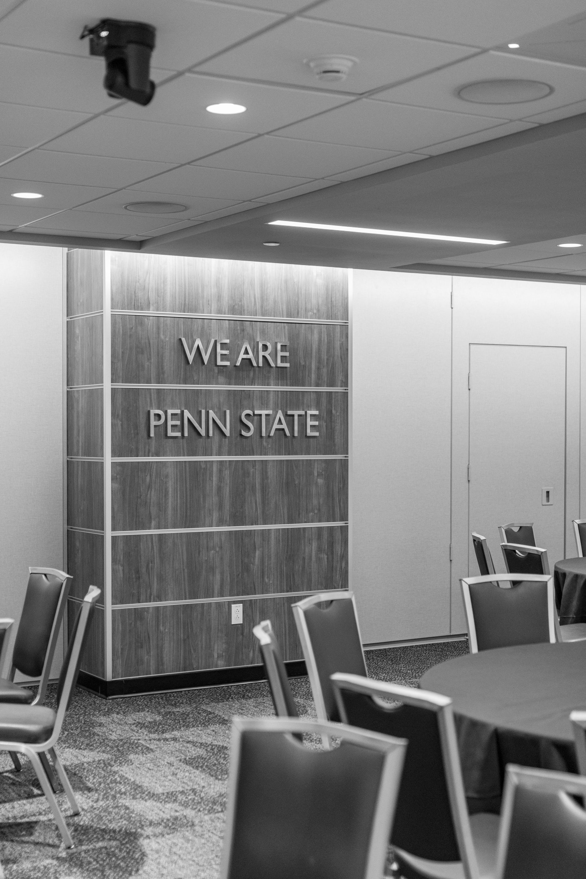 Bryce Jordan Center's conference room with a Penn State banner, tables, and chairs under ceiling lights.