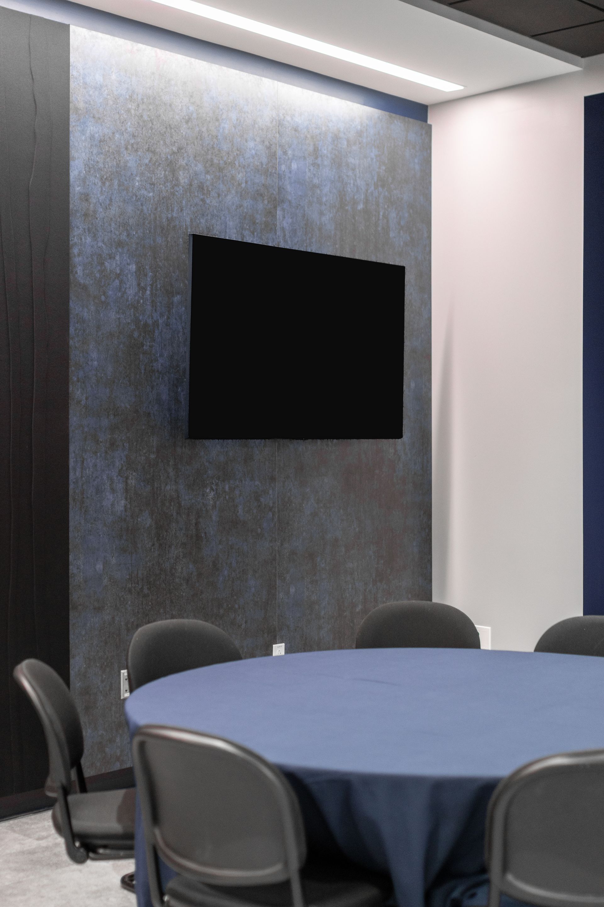 Bryce Jordan Center's modern conference room with round table, black wall-mounted screen, and gray chairs