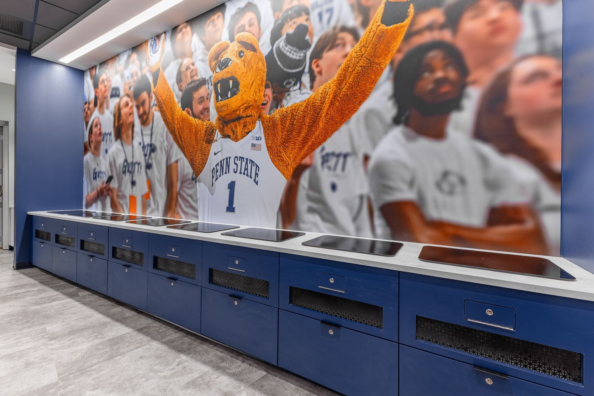 Bryce Jordan Center's blue locker room wall mural of cheering sports fans above matching blue lockers