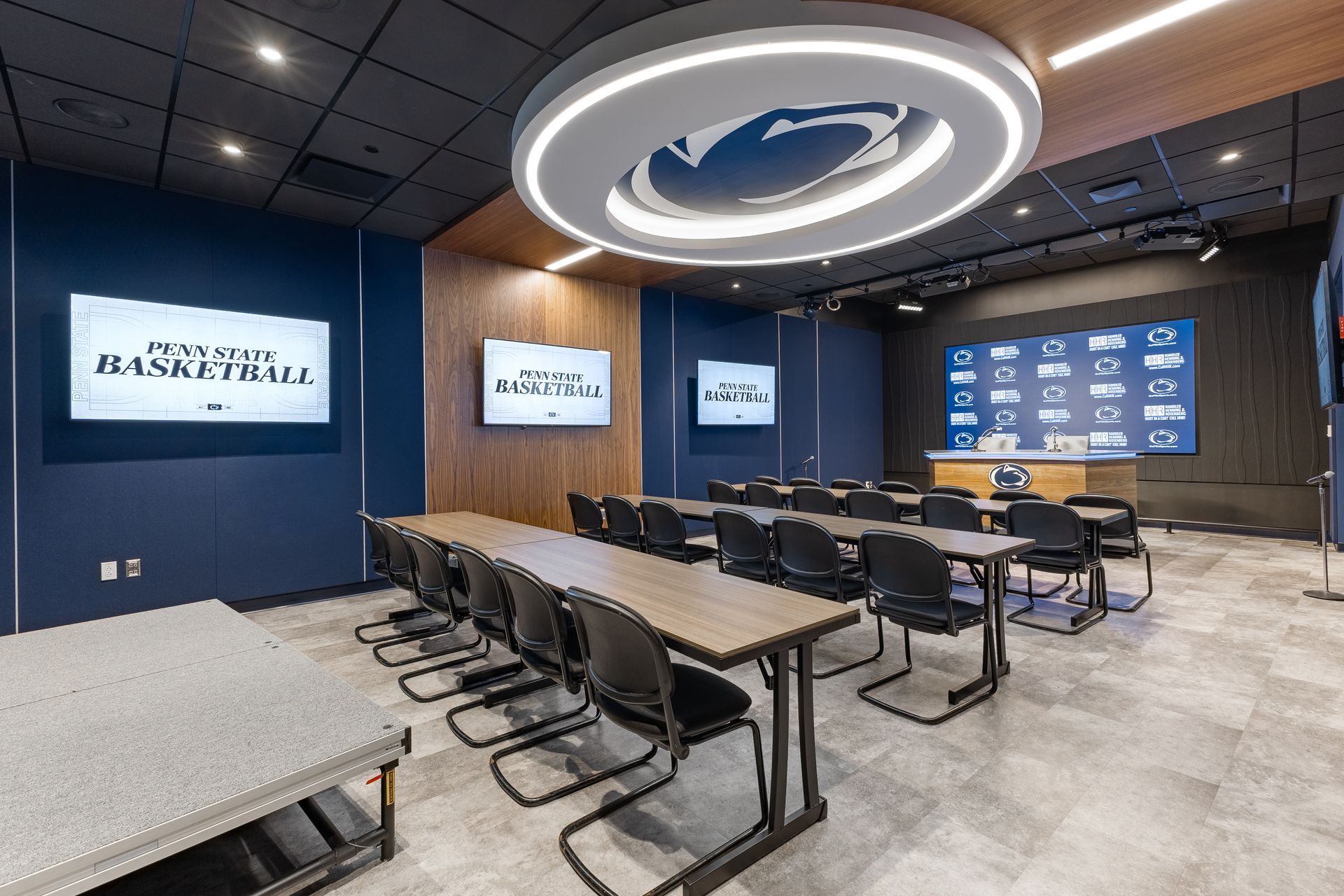 Bryce Jordan Center's modern conference room with rows of chairs, long tables, wall screens, and a circular ceiling light