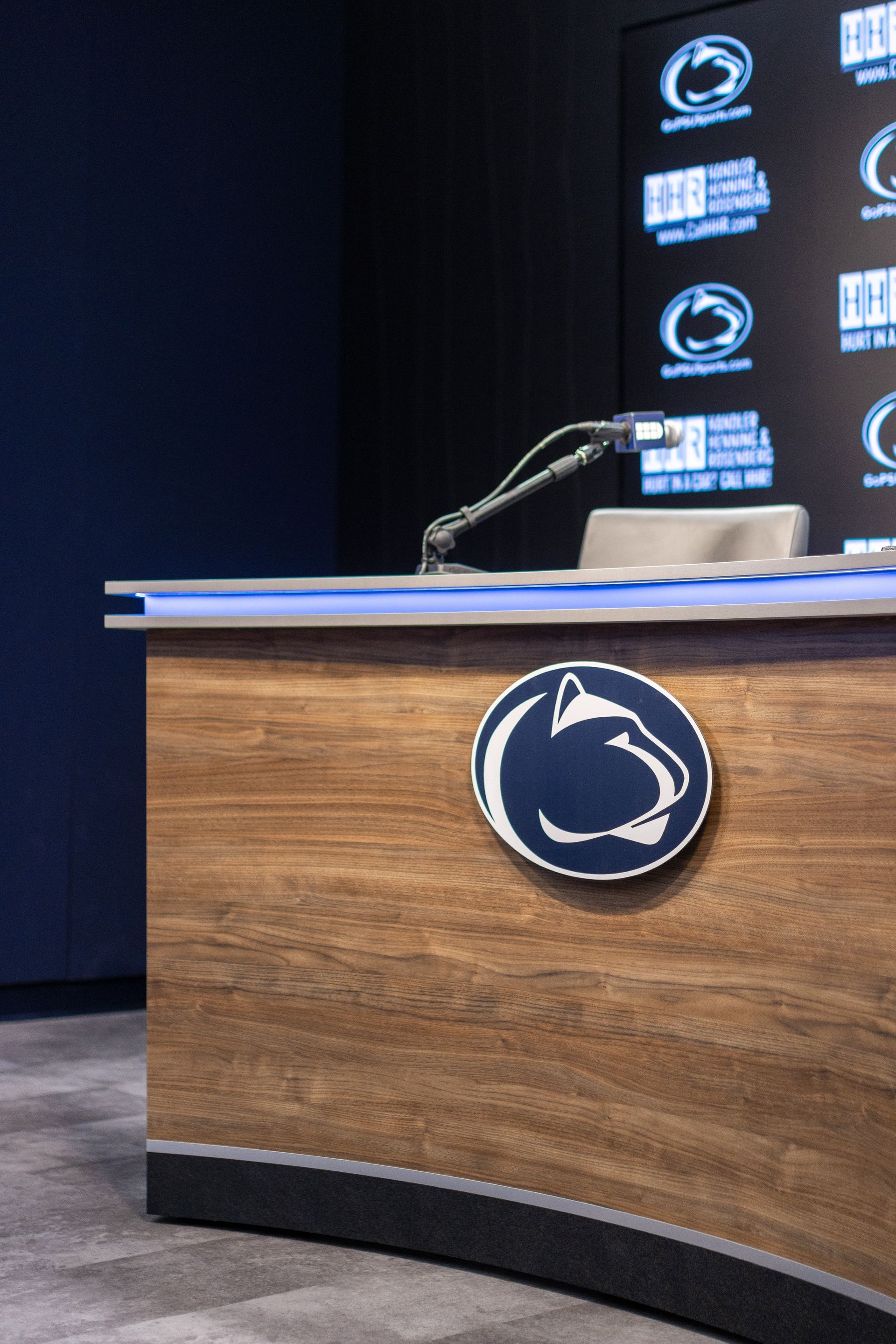 Bryce Jordan Center's wooden podium with a microphone and Penn State logo on a stage backdrop
