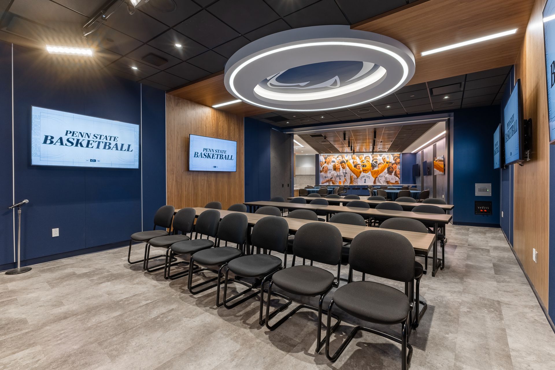 Bryce Jordan Center's modern conference room with rows of black chairs, wall screens, and a stage at the front